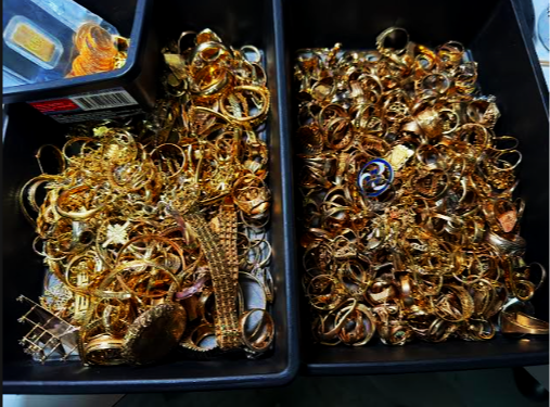 Close-up view of tangled gold necklaces, rings, and old coins inside a bucket at a Scranton gold and silver buying shop.