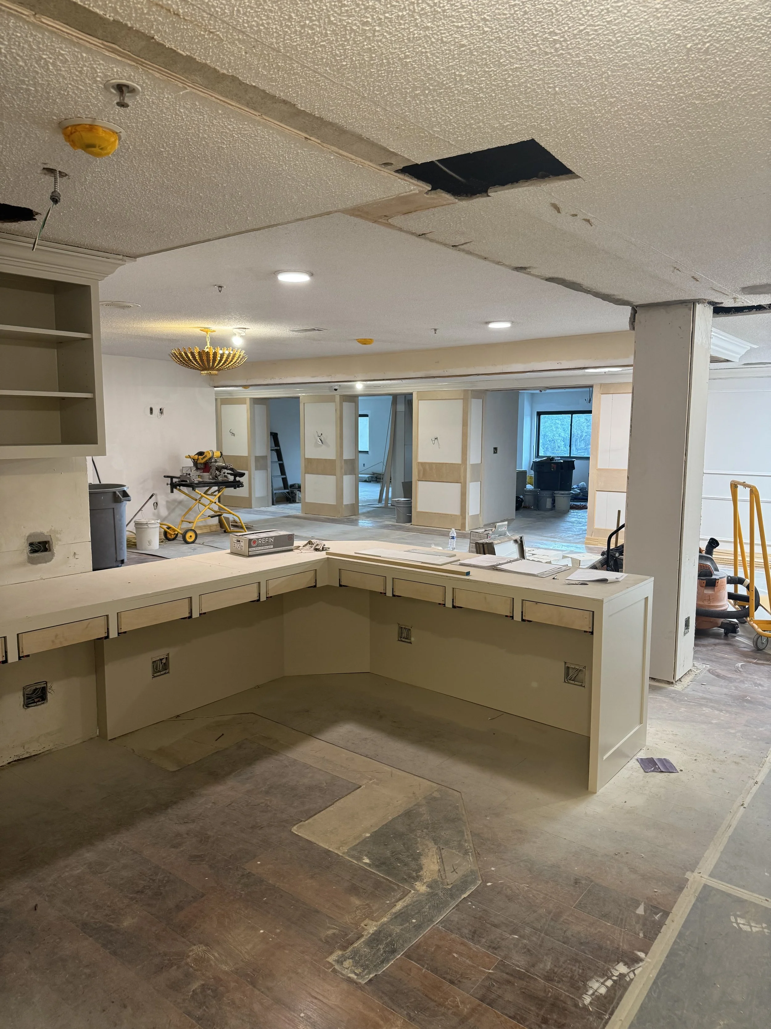 Interior of a house under renovation with missing ceiling tiles, construction tools, and partially finished walls.