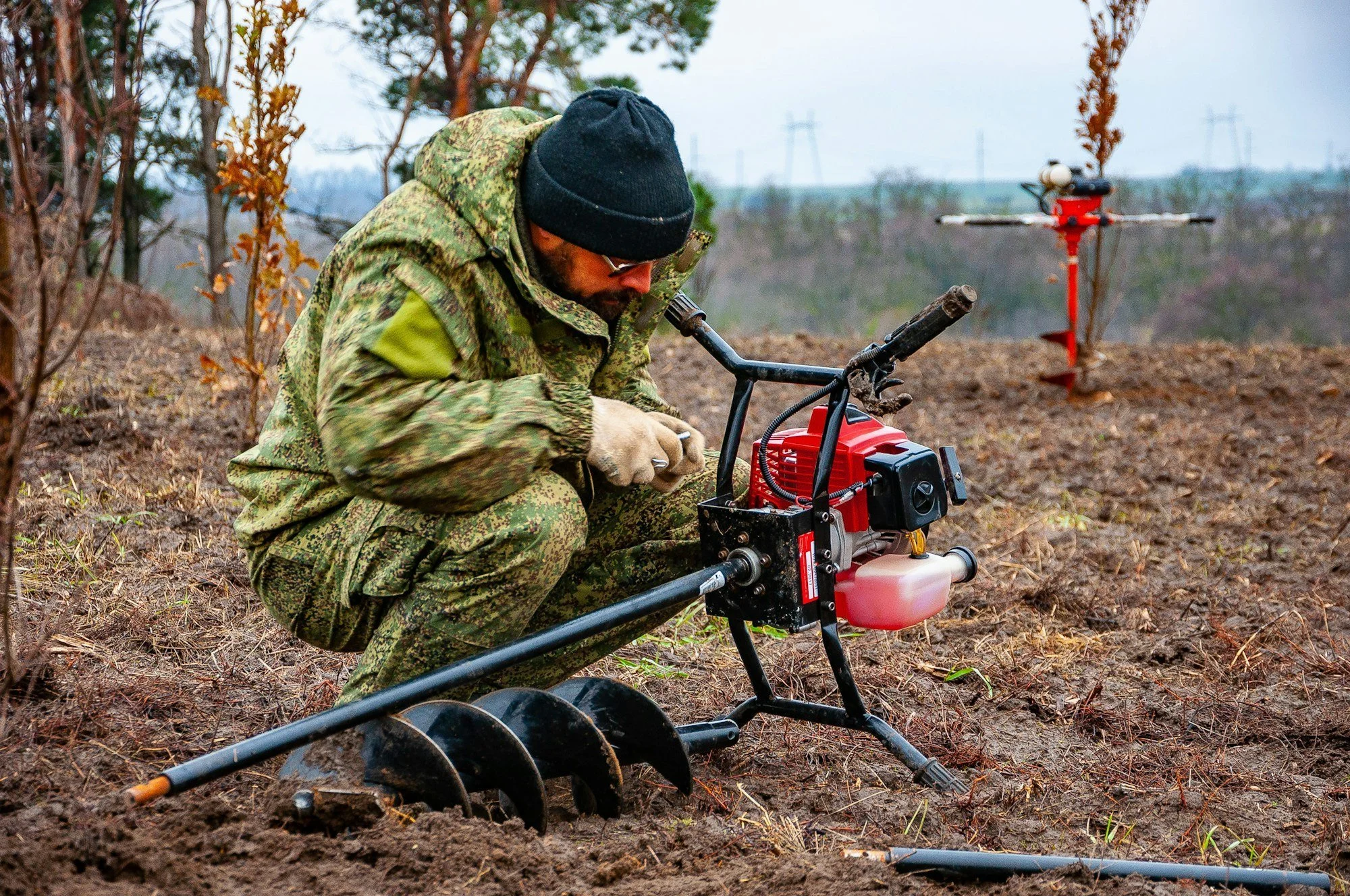 Worker drilling a soil sample with a powered auger