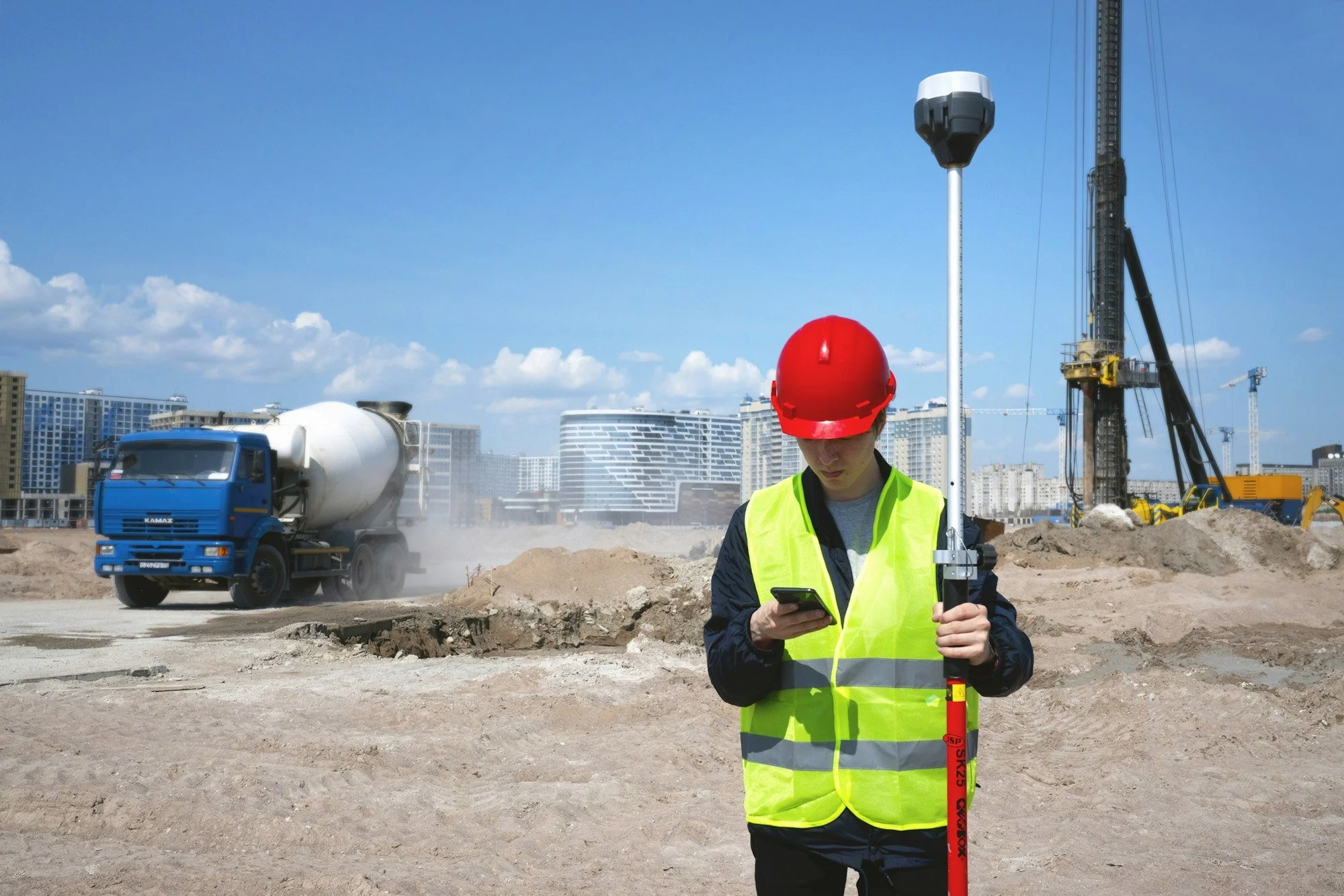 Site worker using a GPS survey pole to set out levels on a building site