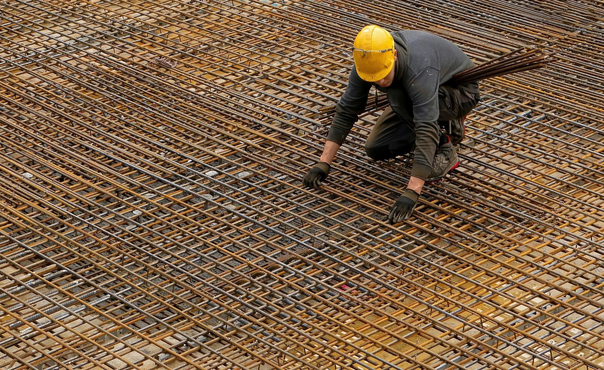 Worker tying steel reinforcement mesh for a concrete slab