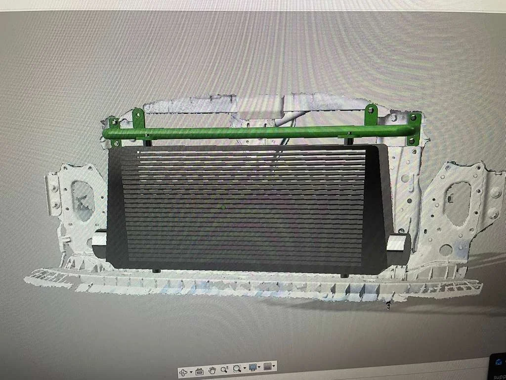 A computer-aided design model of a vehicle radiator mounted to a frame with green support bars.