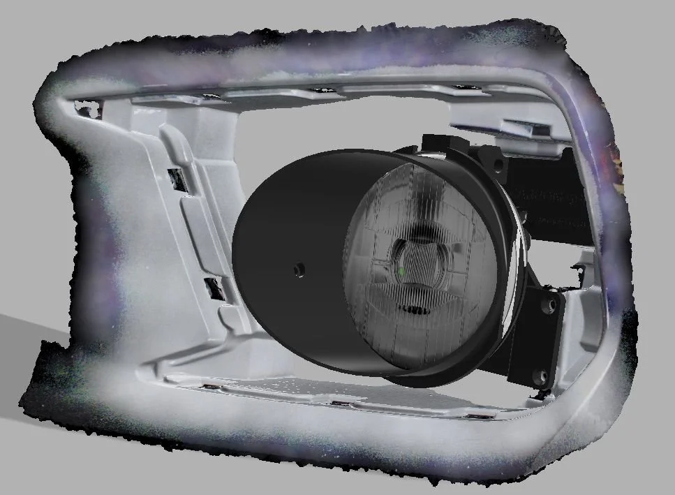 A partially disassembled car headlight with the outer cover removed, showing the internal reflective surface and bulb holder.