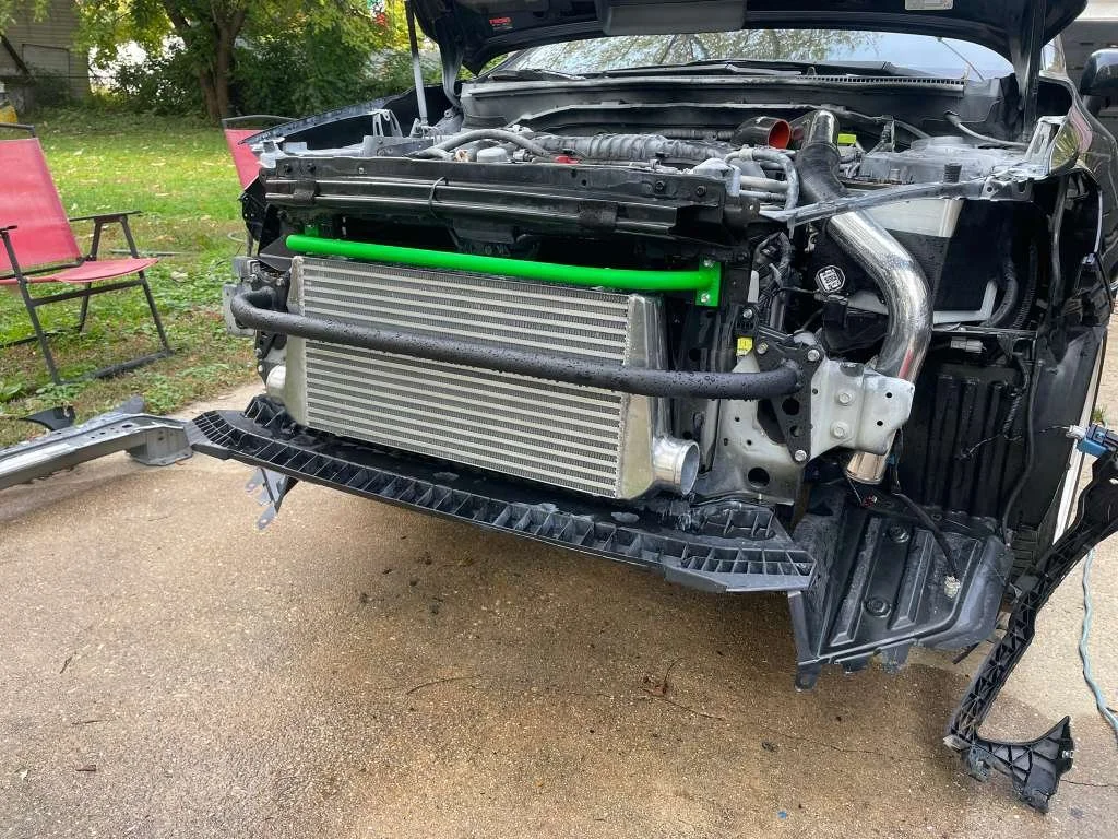 Close-up of a car with its front bumper removed, revealing the radiator, intercooler, and various engine components.