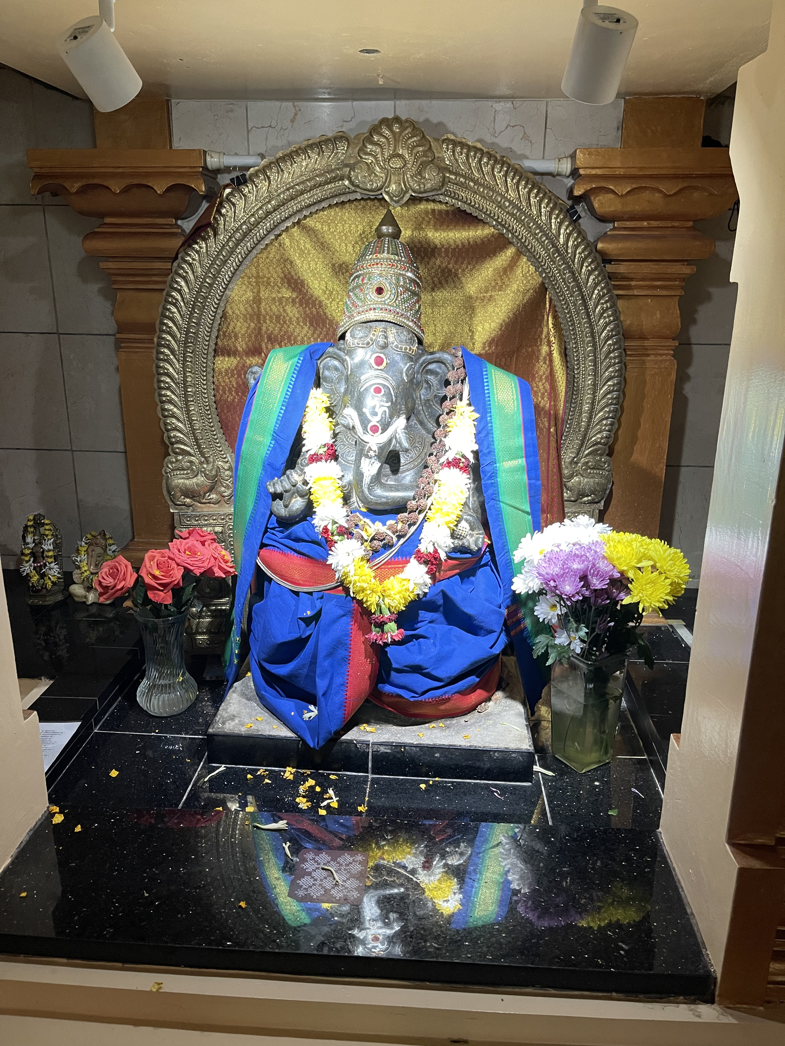 Hindu temple shrine with Ganesha statue decorated with flowers inside a place of worship.