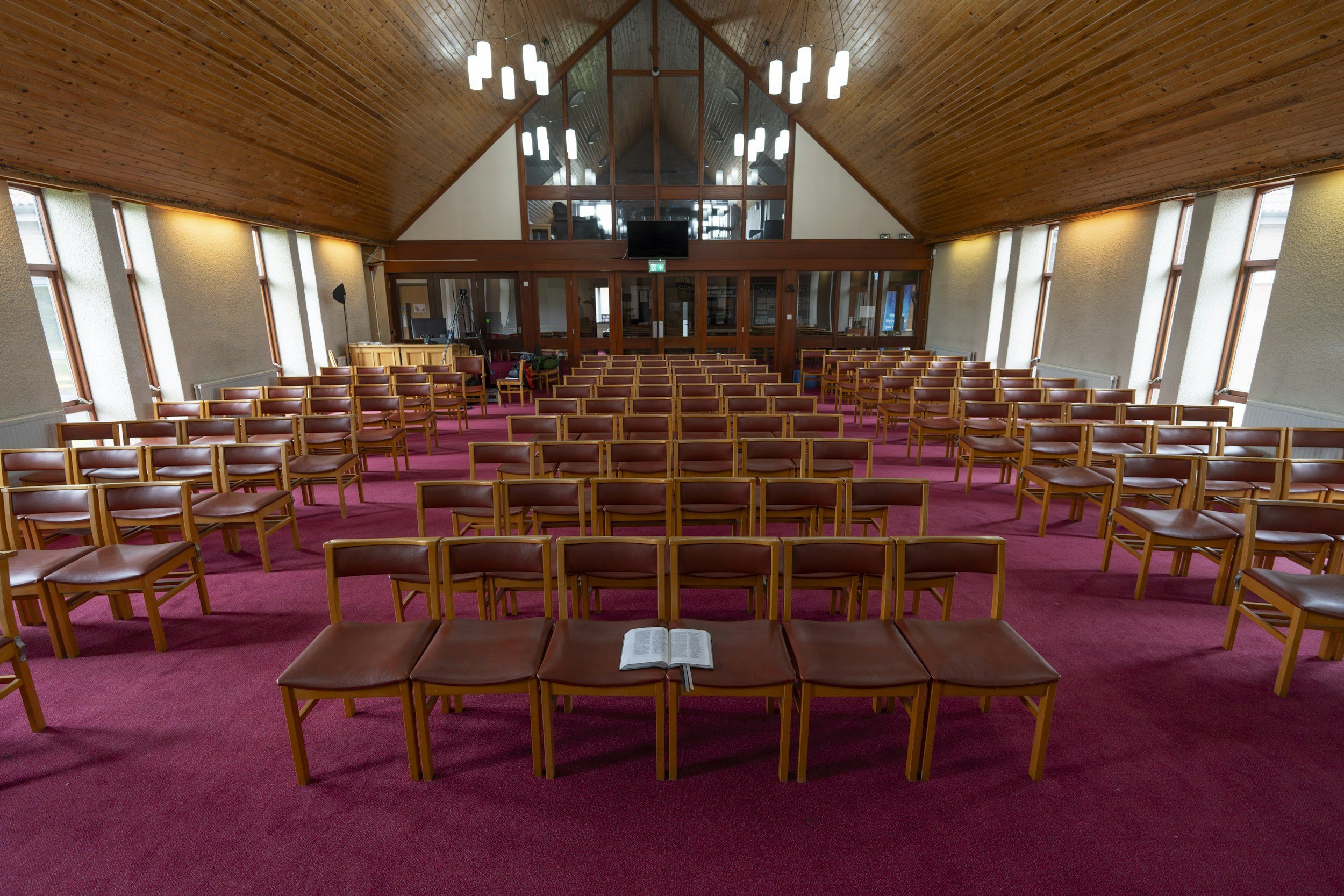 Large church sanctuary with rows of seating and wooden ceiling inside a worship space.