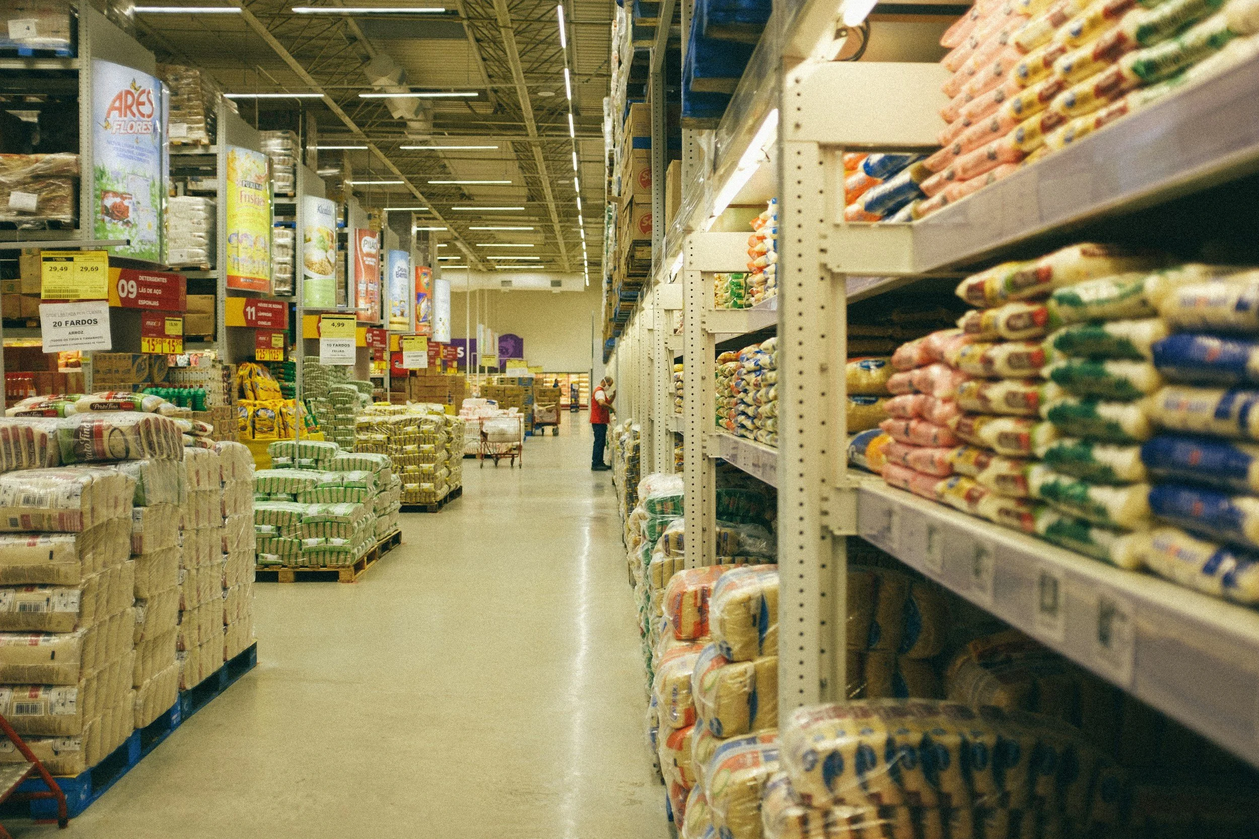 Aisle in a grocery store with shelves stocked with rice bags and other bulk food products.
