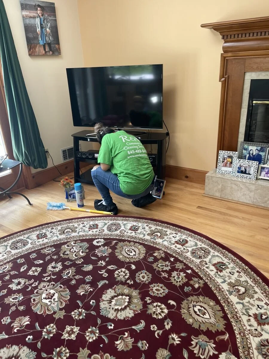 cleaning staff dusting entertainment center and living room surfaces during residential house cleaning in Poughkeepsie NY