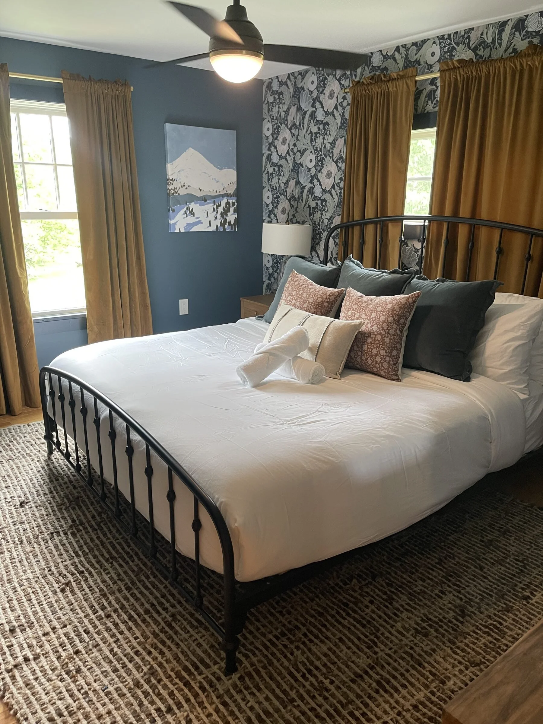 Clean Airbnb bedroom with neatly made bed, decorative pillows, and folded towels prepared for guest arrival.