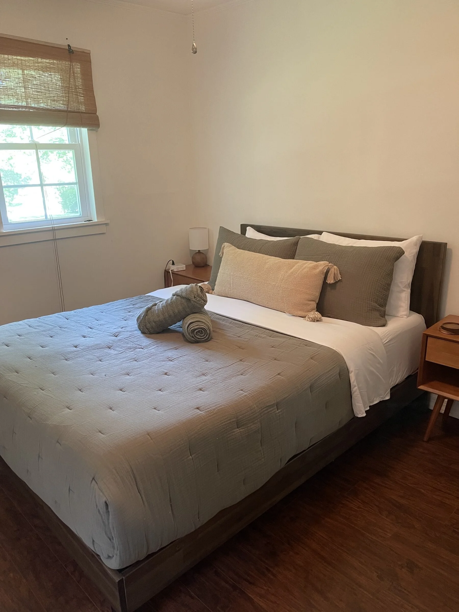 Clean Airbnb bedroom with neatly made bed, decorative pillows, folded towels, and guest-ready staging