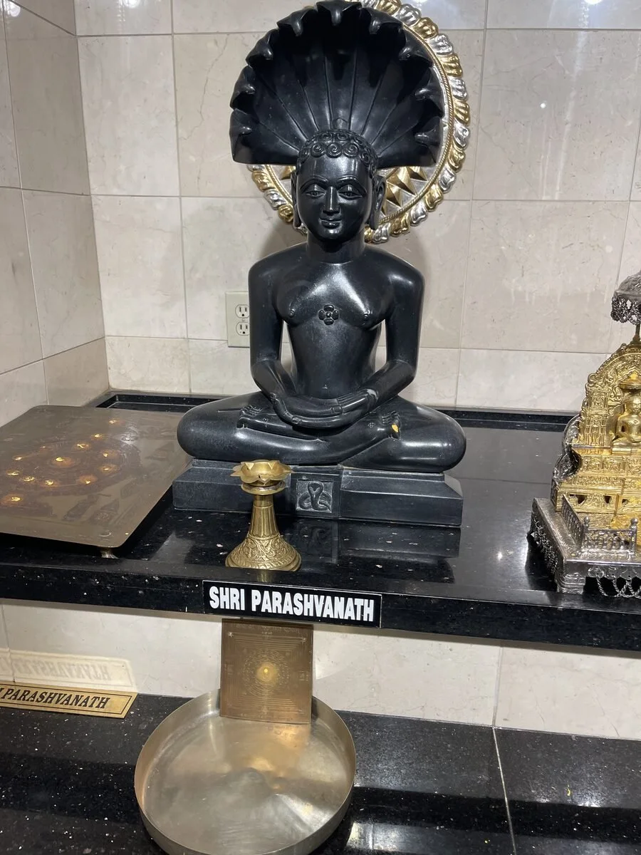 Polishing and cleaning black temple statue and surrounding shrine.