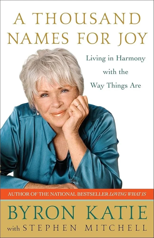 Book cover titled 'A Thousand Names for Joy' by Byron Katie with Stephen Mitchell, featuring a woman with short gray hair wearing a teal silk blouse, resting her chin on her hand.