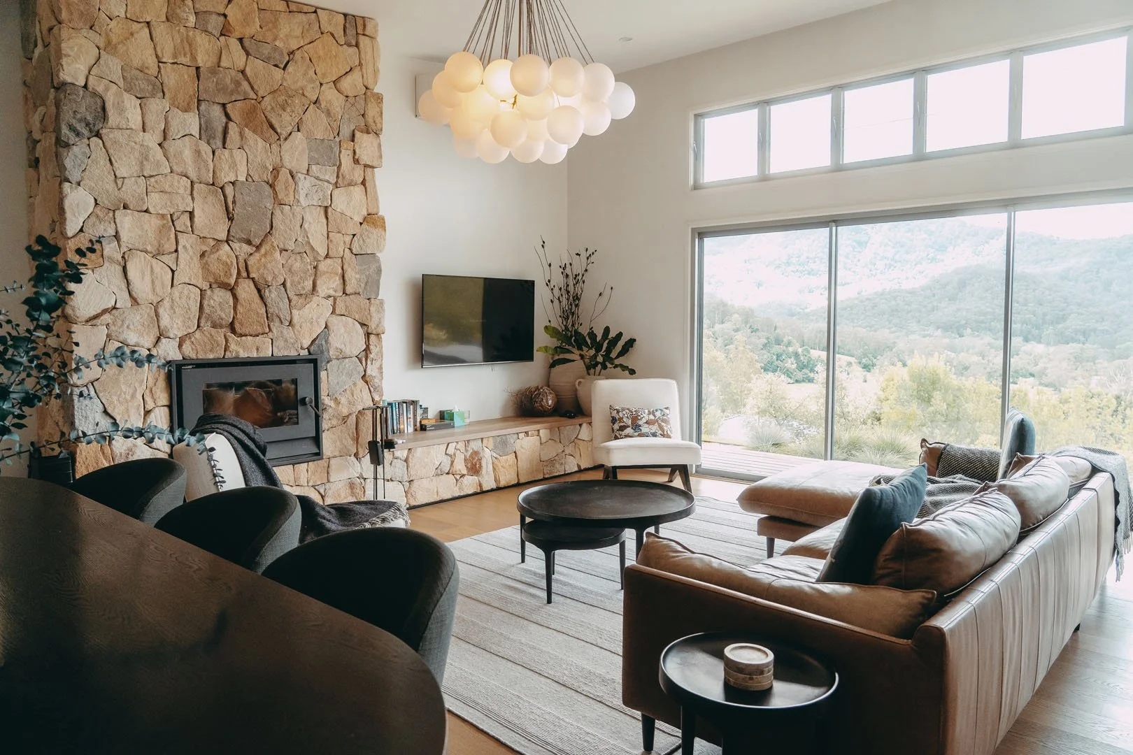 Luxury lodge living room with fireplace, comfortable seating, and panoramic escarpment views in Kangaroo Valley