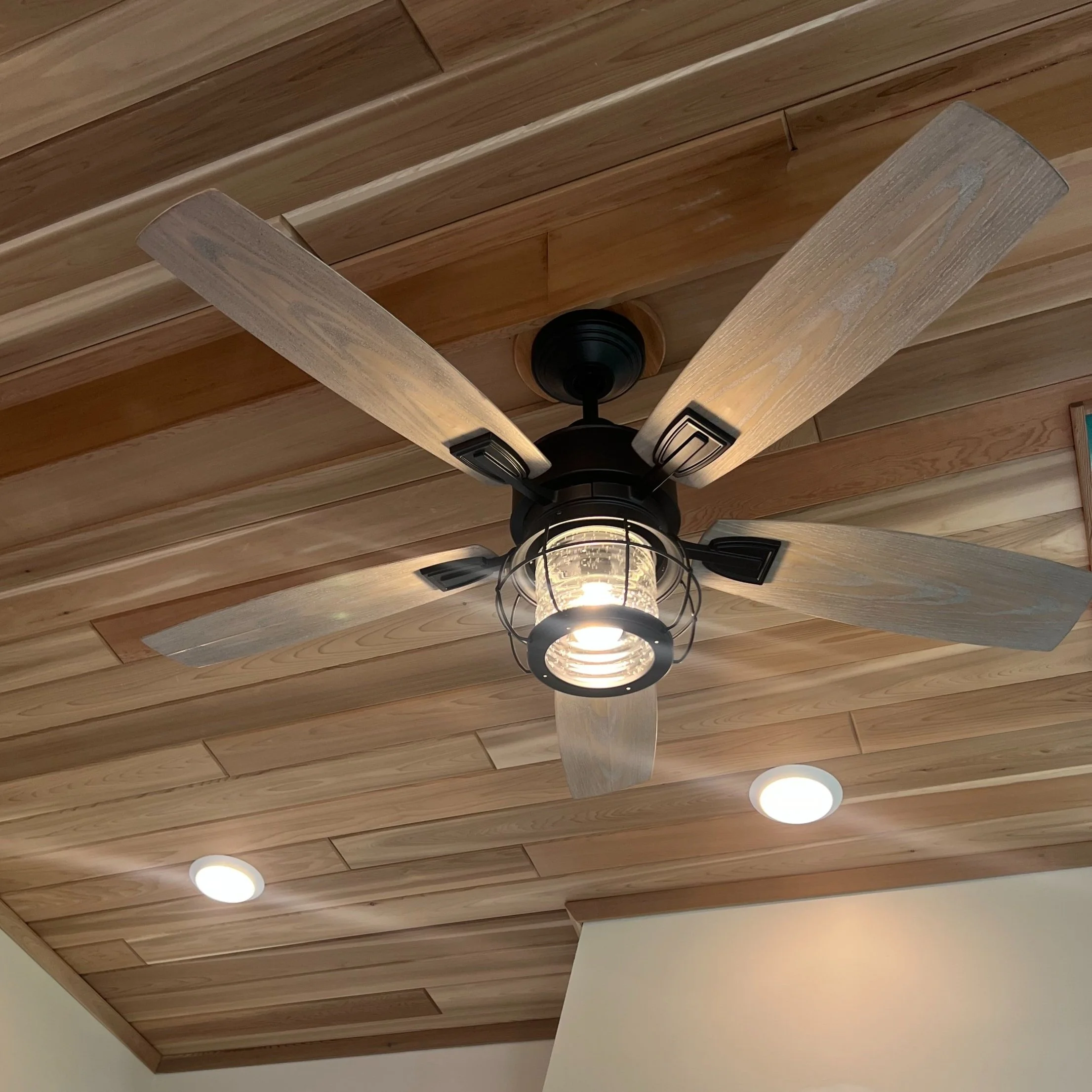 Wood-blade ceiling fan with integrated cage light fixture – professionally installed by Walter Electrical Contractors.
