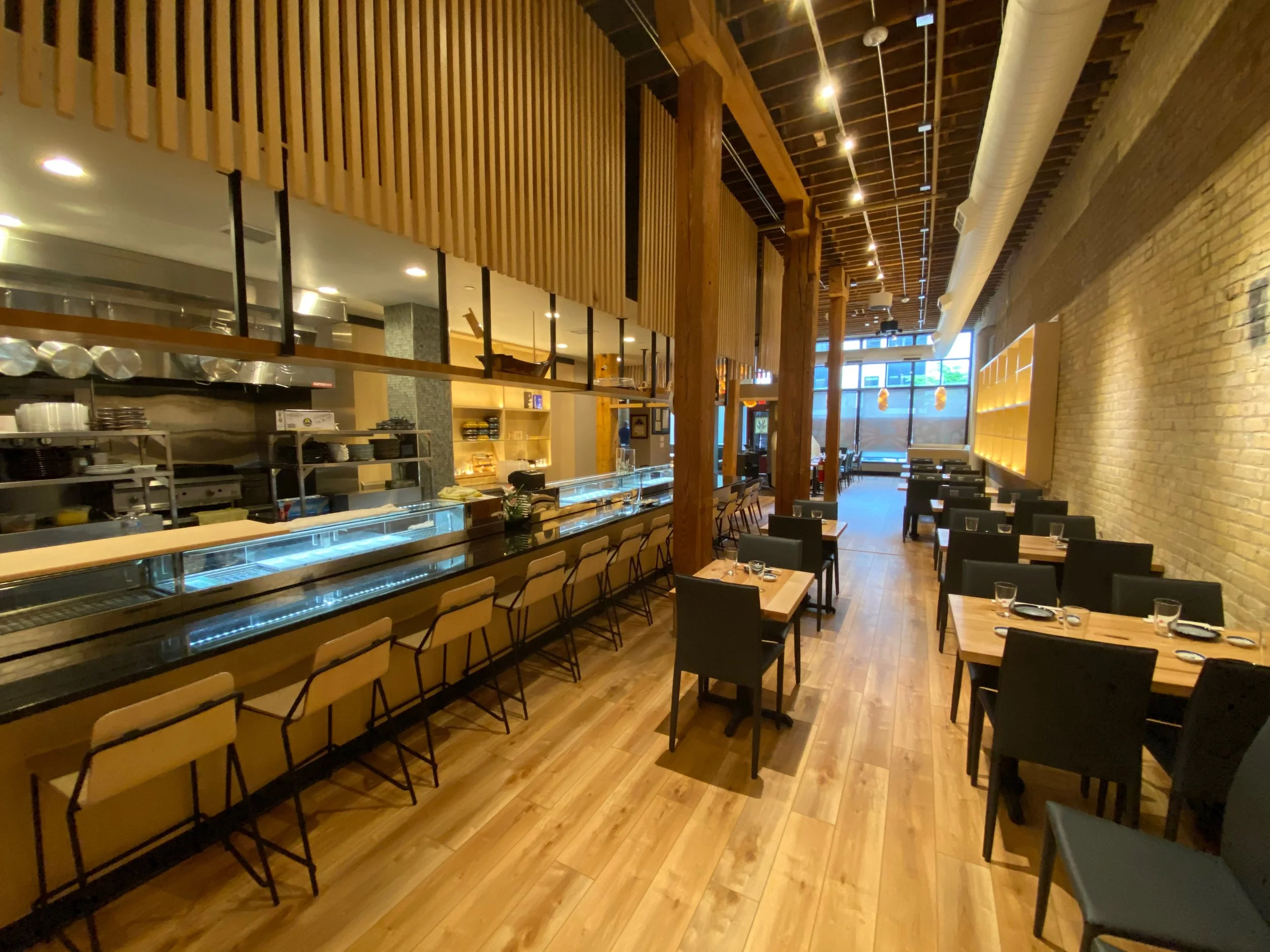 Commercial electrical installation by Walter Electrical Contractors in Minnesota, including lighting for the sushi counter, dining area illumination, and power for kitchen equipment in a modern restaurant with open layout.