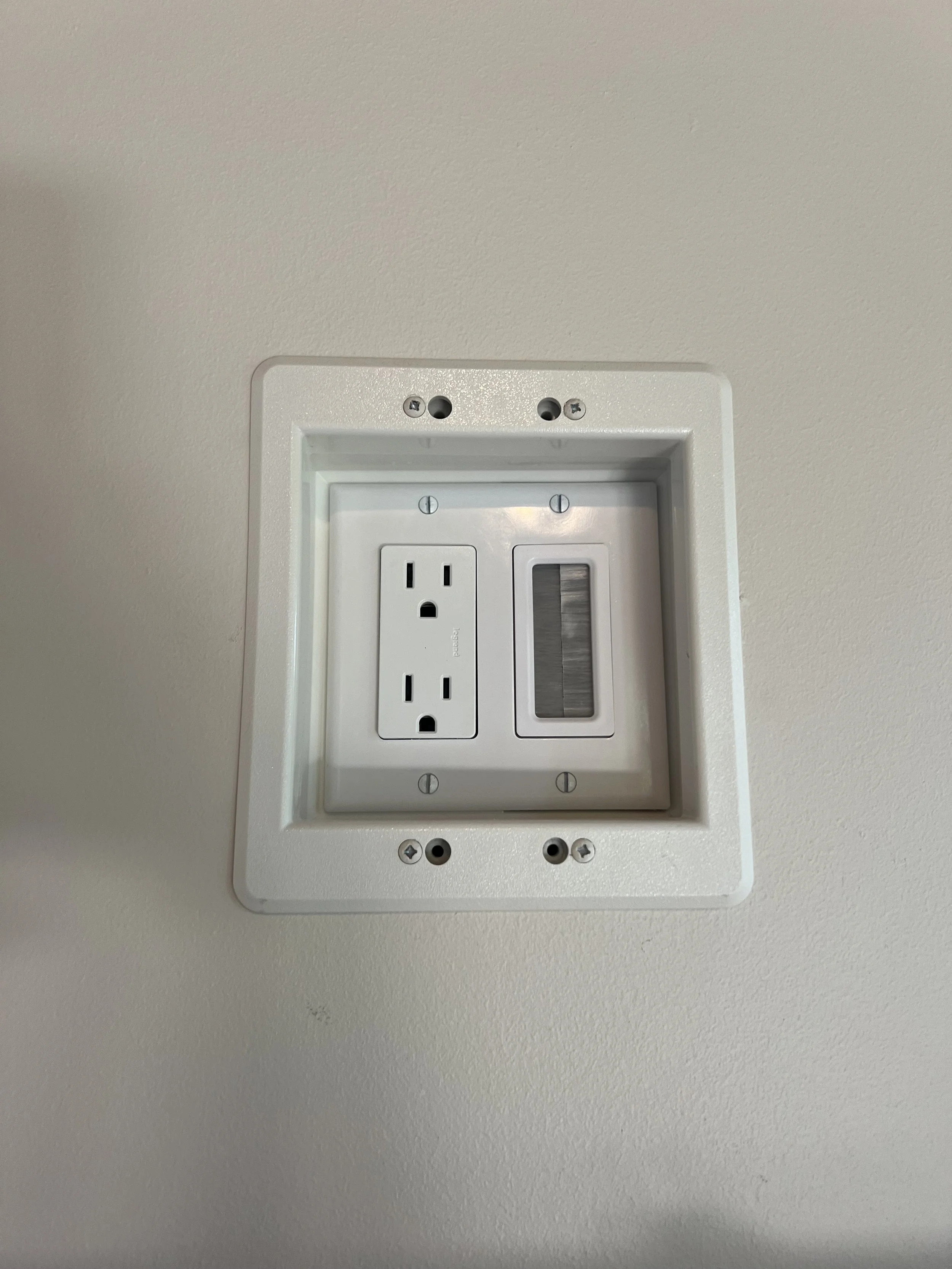 Wall-mounted TV power and low-voltage outlet installation with switch panel on a white wall – installed by Walter Electrical Contractors.
