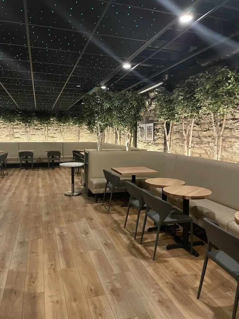 Commercial electrical work by Walter Electrical Contractors in Minnesota, featuring ceiling lights with a starry effect, ambient lighting for booths, and wall-mounted lighting accents along a stone wall.