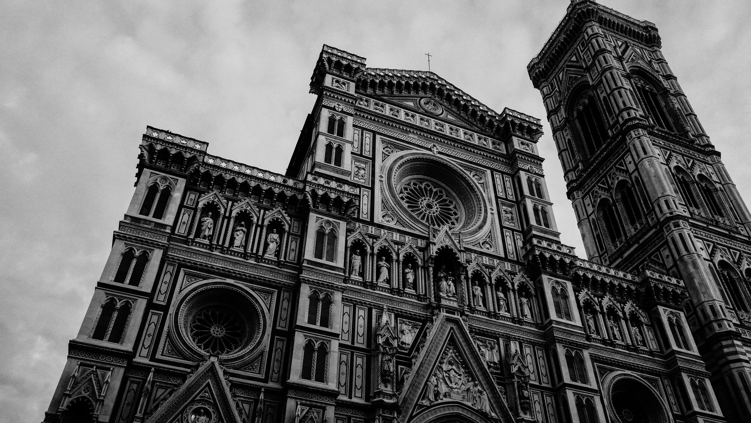 Black-and-white photograph of the cathedral's elaborate Gothic facade with sculptures, large circular windows, and a tall bell tower