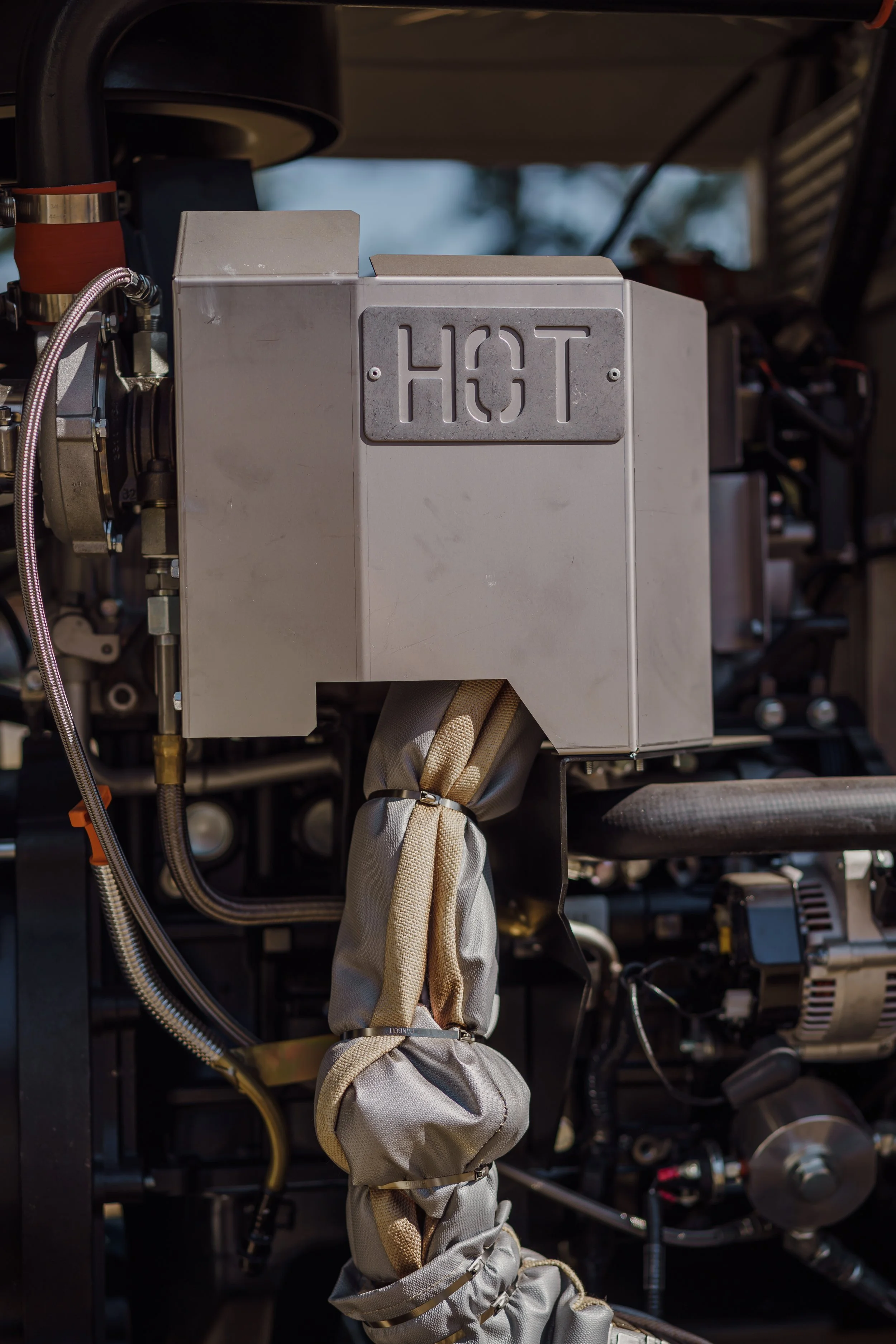 Close-up of an industrial heat exchanger with a metal cover labeled 'HOT' and insulated piping.