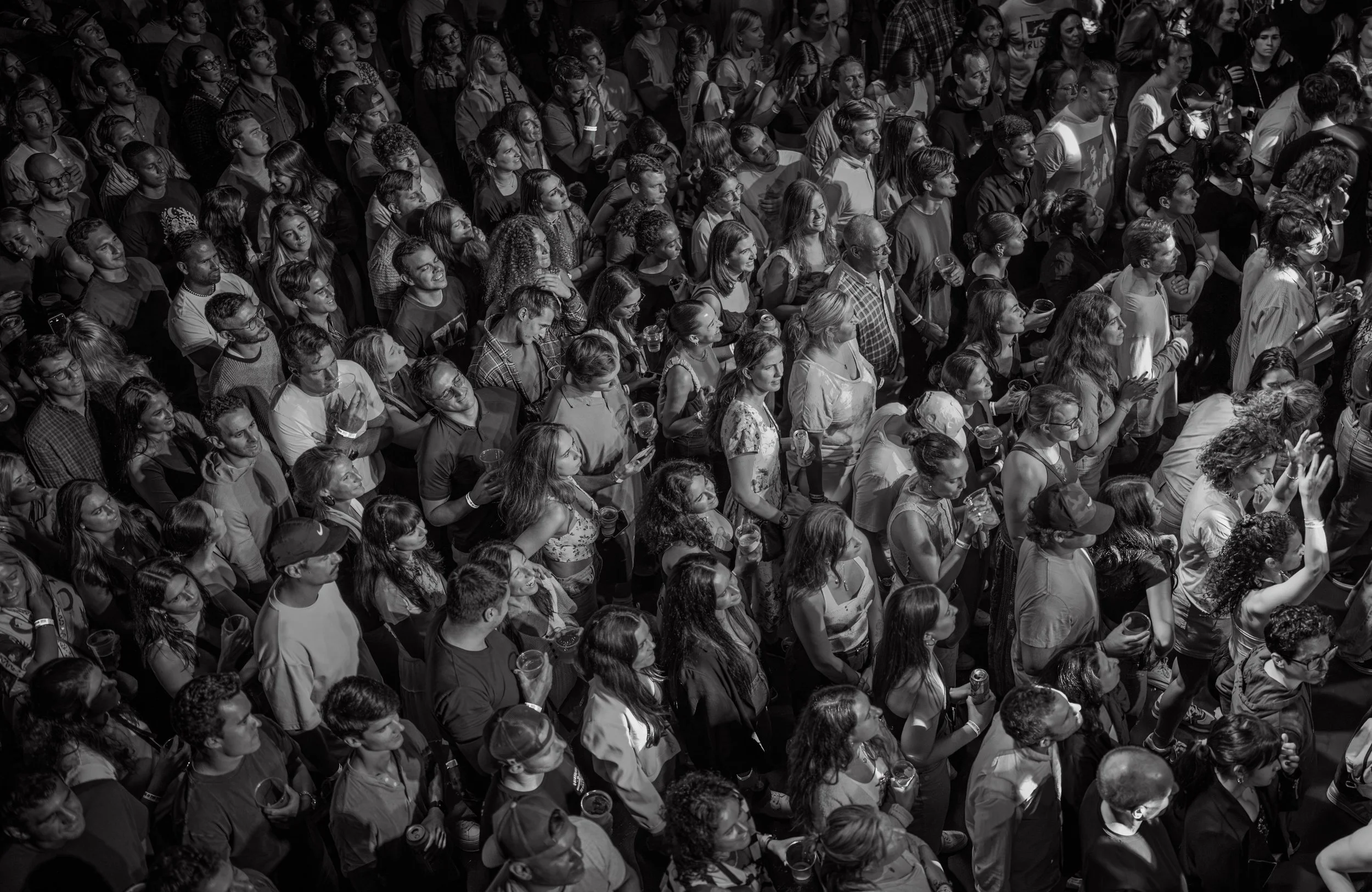 A large crowd of people attending an event, viewed from above in black and white.