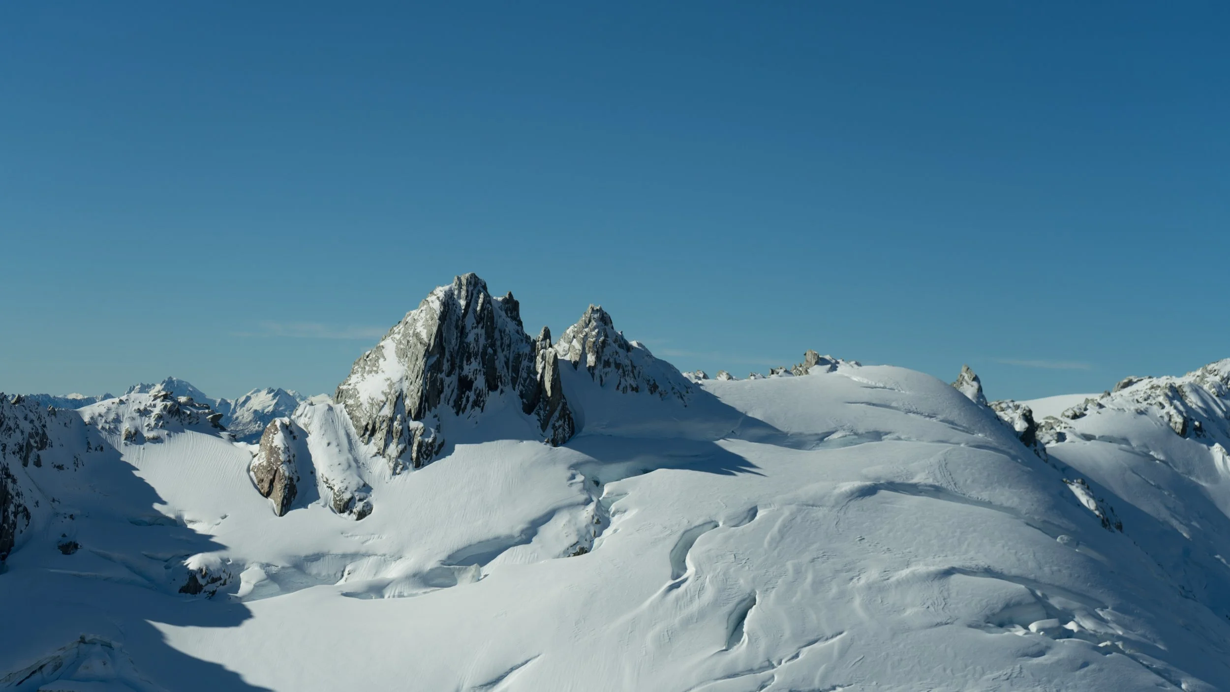 Snow-covered mountain peaks under a clear blue sky
