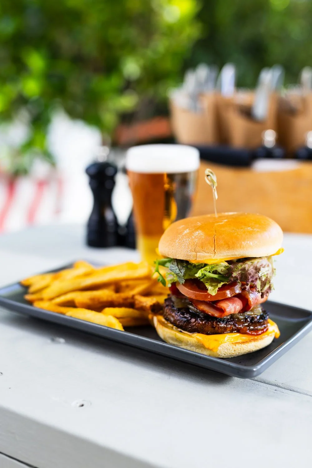 Interior of a modern restaurant with wooden chairs and tables, a bar area in the background, and decorative partitions.