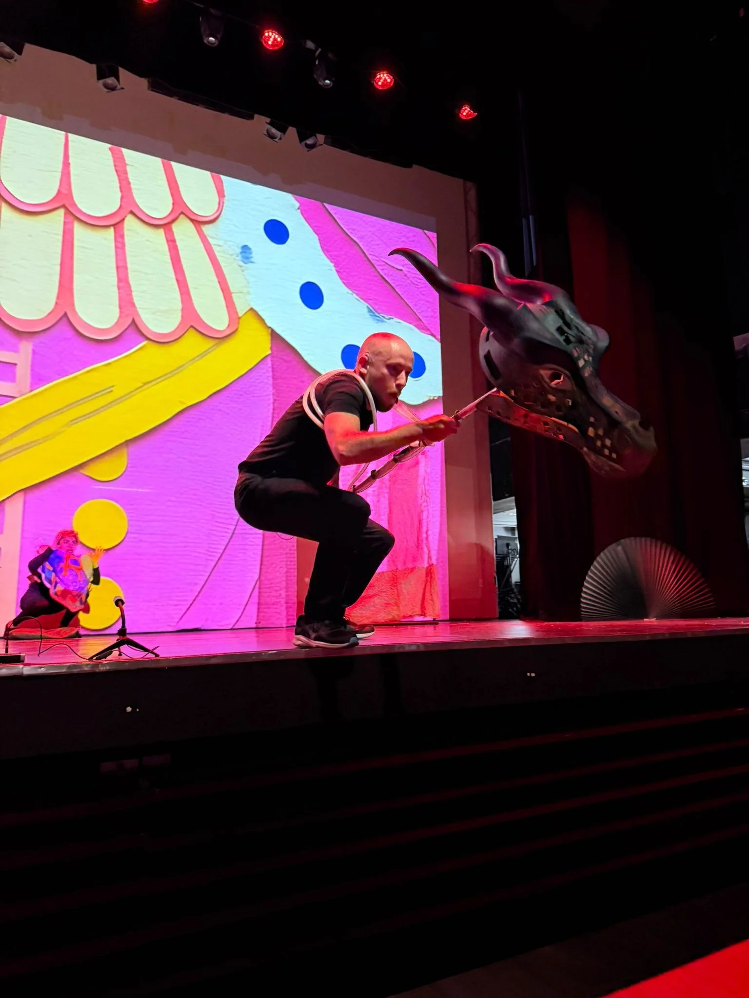 Professional actors, Hamish Campbell, as Dragon performing a dramatic scene from The Paper Bag Princess on a school stage in Hong Kong for an attentive student audience.