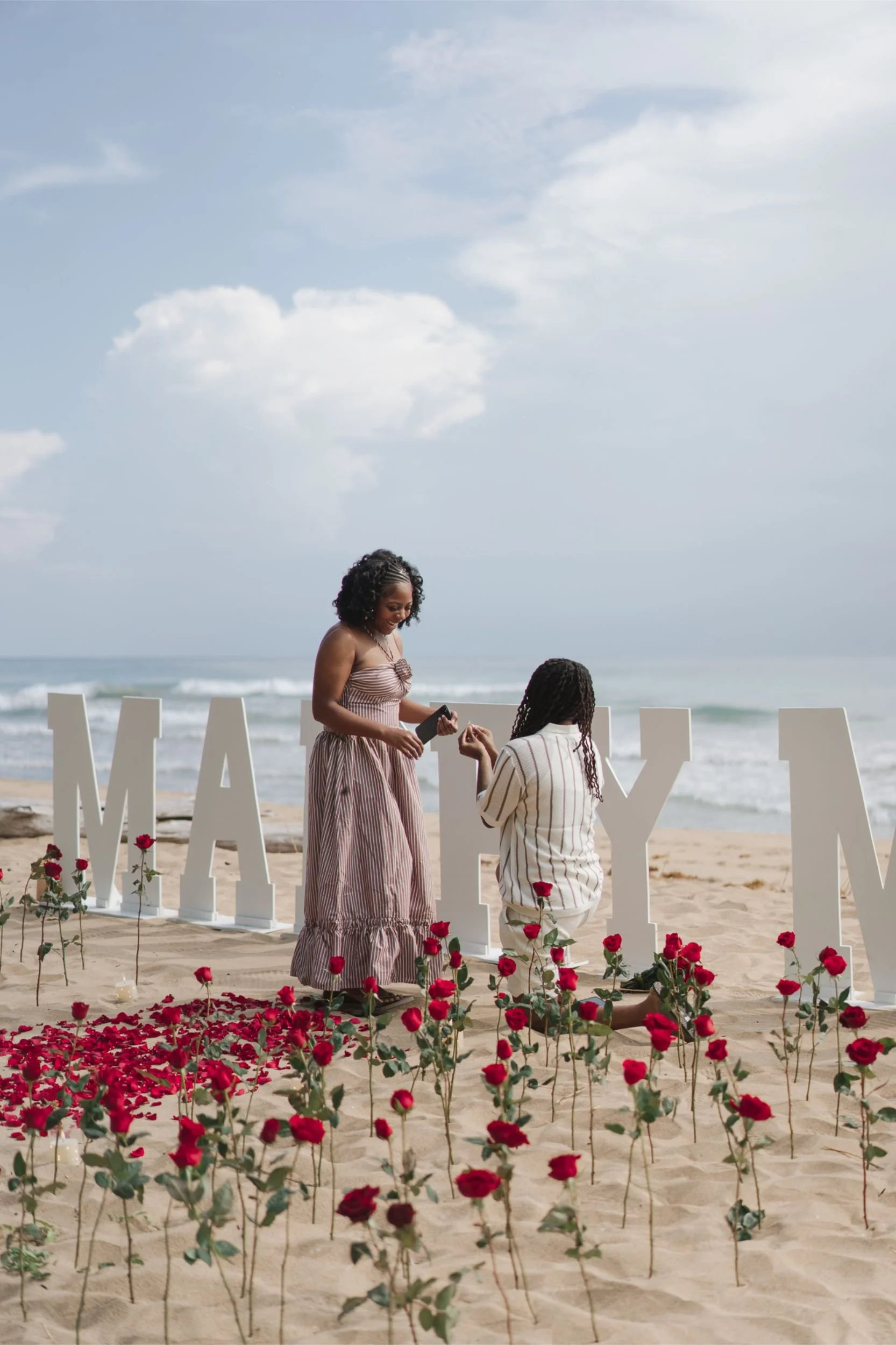 Beach proposal in Costa Rica with red roses and oversized marry me letters in the sand