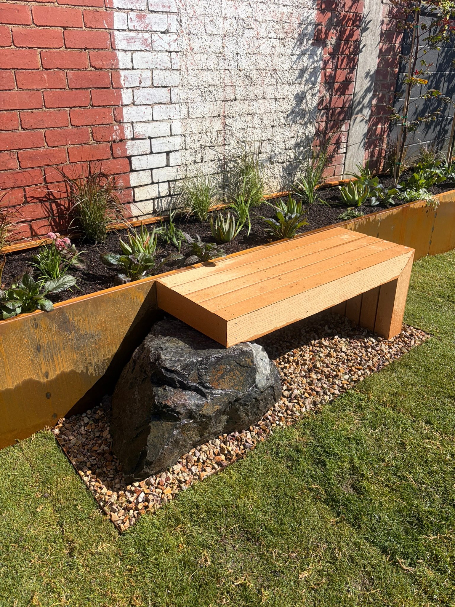 Compact garden with custom-built furniture pieces surrounded by lush greenery