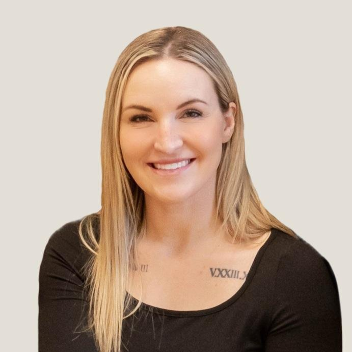 Smiling woman with long blonde hair wearing a black top, against a plain background.