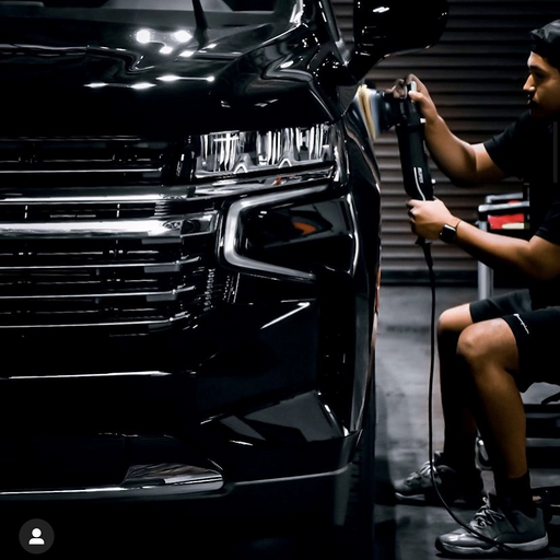 Person polishing a black car in a garage.