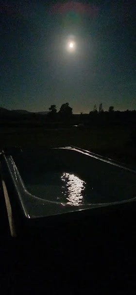 Nighttime with a bright moon in the sky, across the sauna plunge batth
