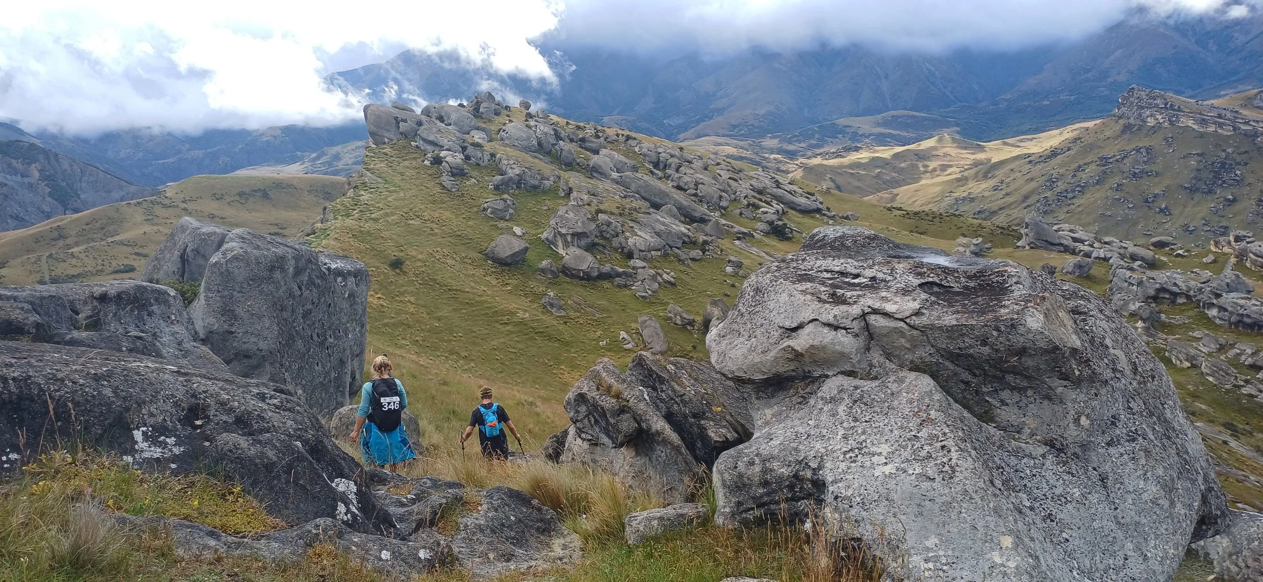 Runners in the local trail running event, Feel The Burn, crossing the rocky landscape of Flock Hill