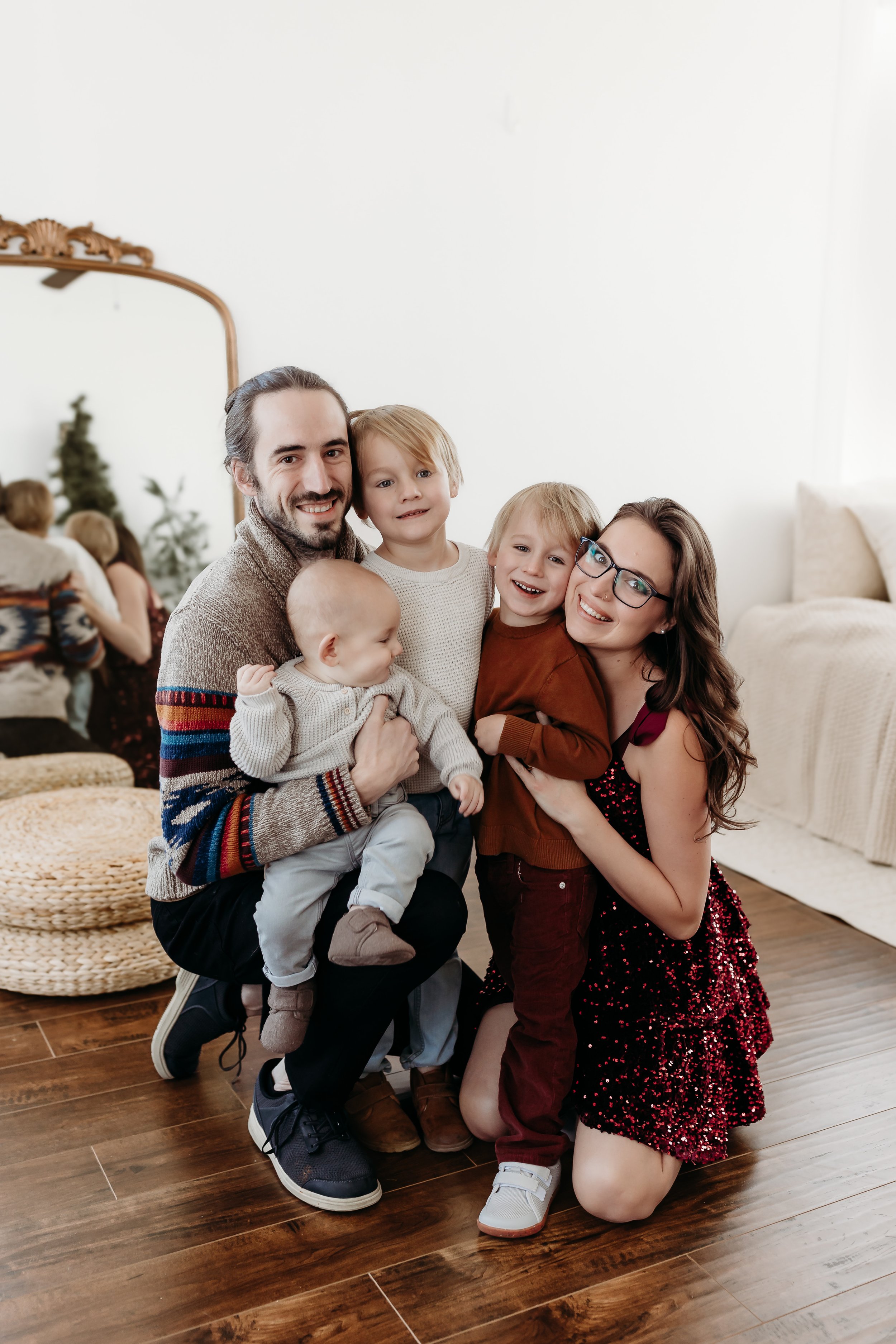 Family of six celebrating together indoors, with Christmas decorations in background.