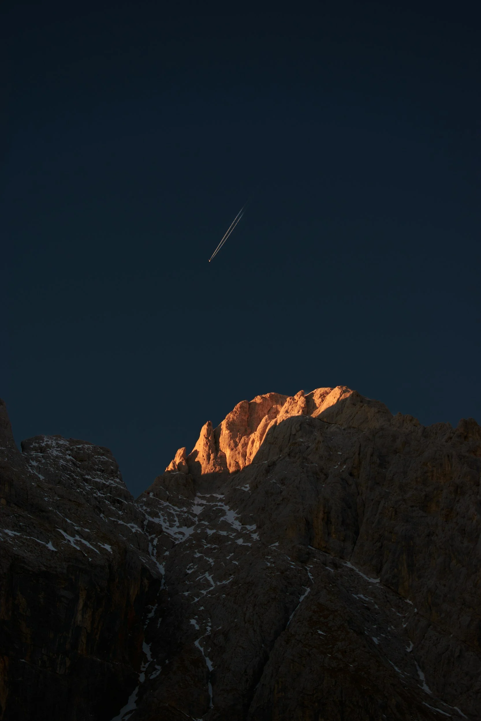 A photo of a mountain with an airplane in the sky