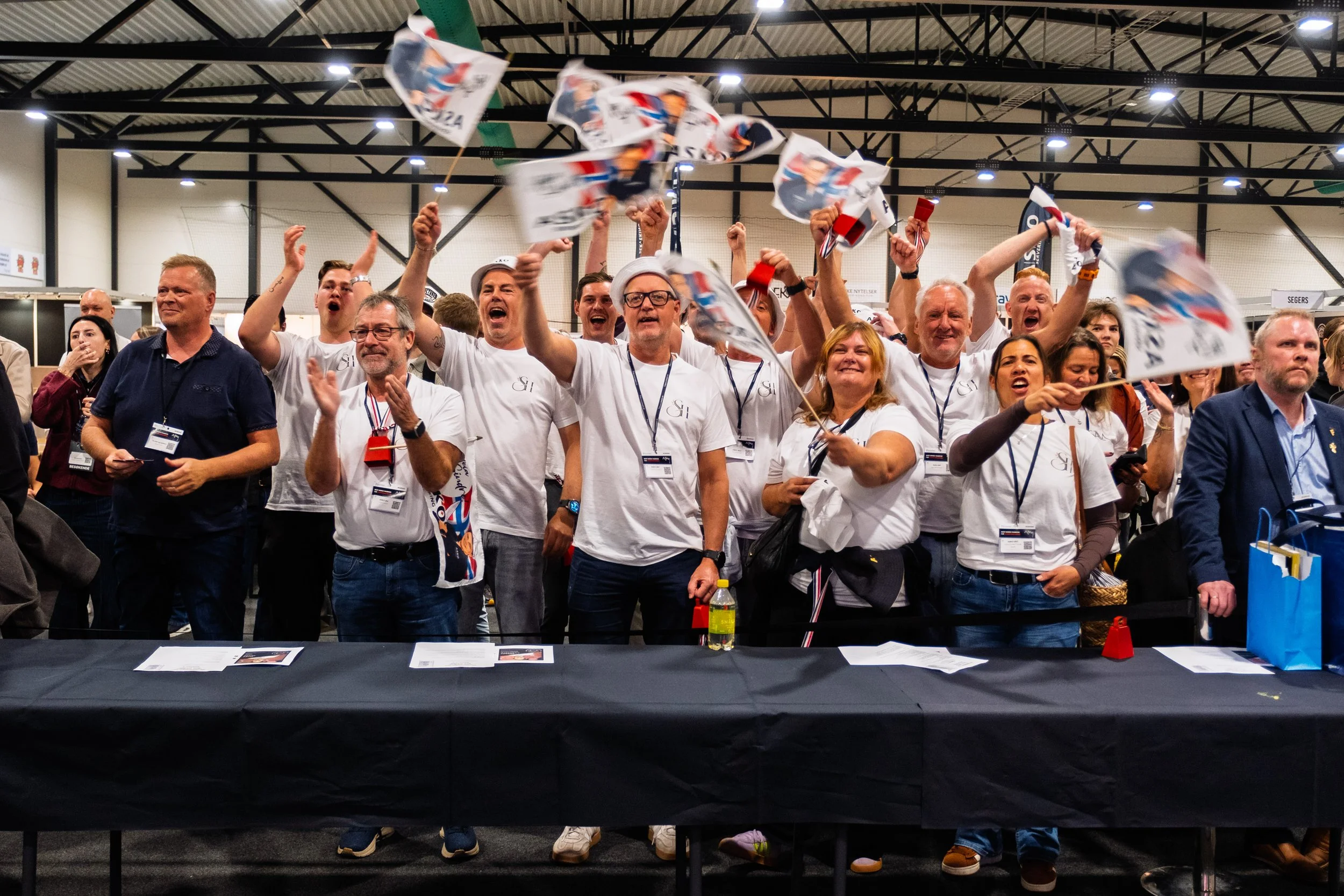 Publikum og støttespillere jubler og vifter med flagg under NM i kokkekunst 2026 i Trondheim.