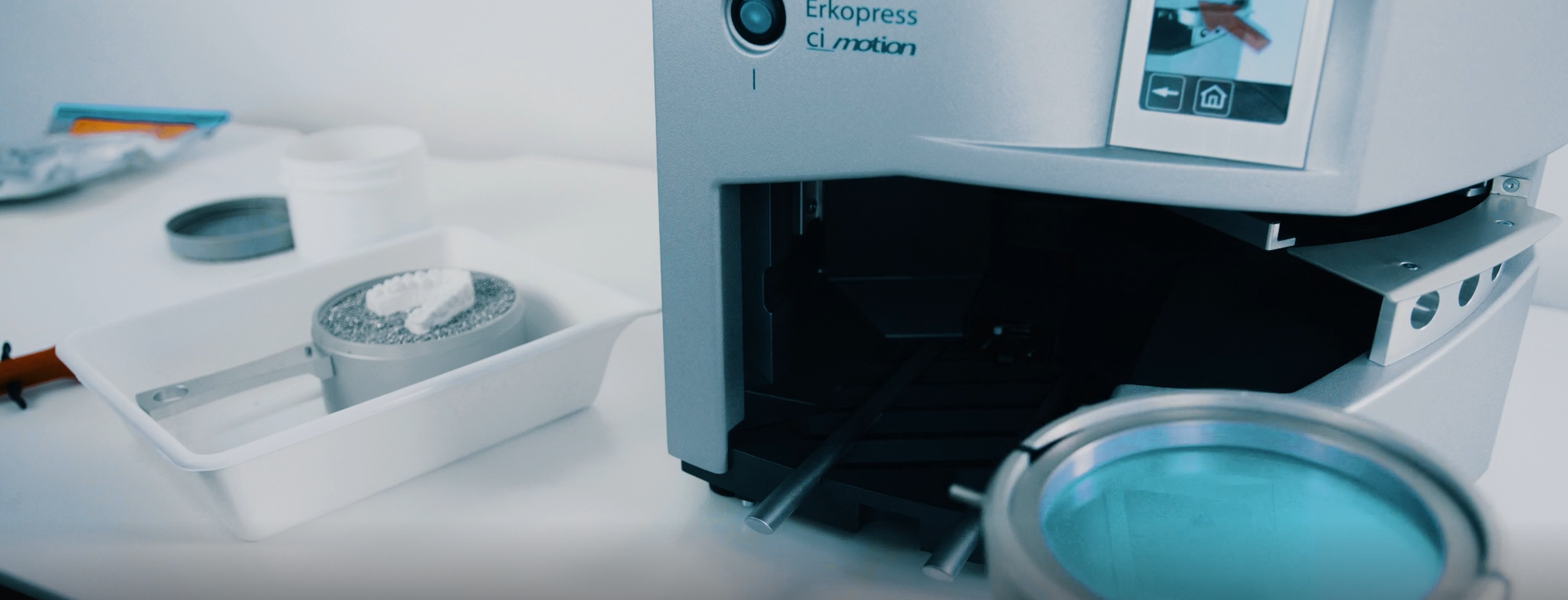 Laboratoriuminstrument met digitale bediening en polijstgereedschap, omgeven door kleine containers en onderdelen.