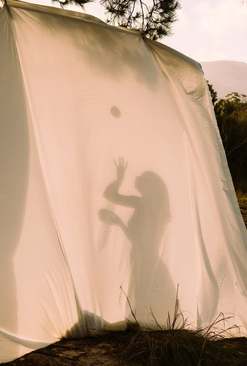 Sinnlichkeits und Weiblichkeitsretreat für Frauen in Portugal. Frauen kommen am Meer im Körper an und erleben Lebendigkeit, Präsenz und innere Kraft in geschütztem Rahmen. Frau hinter Leinwand