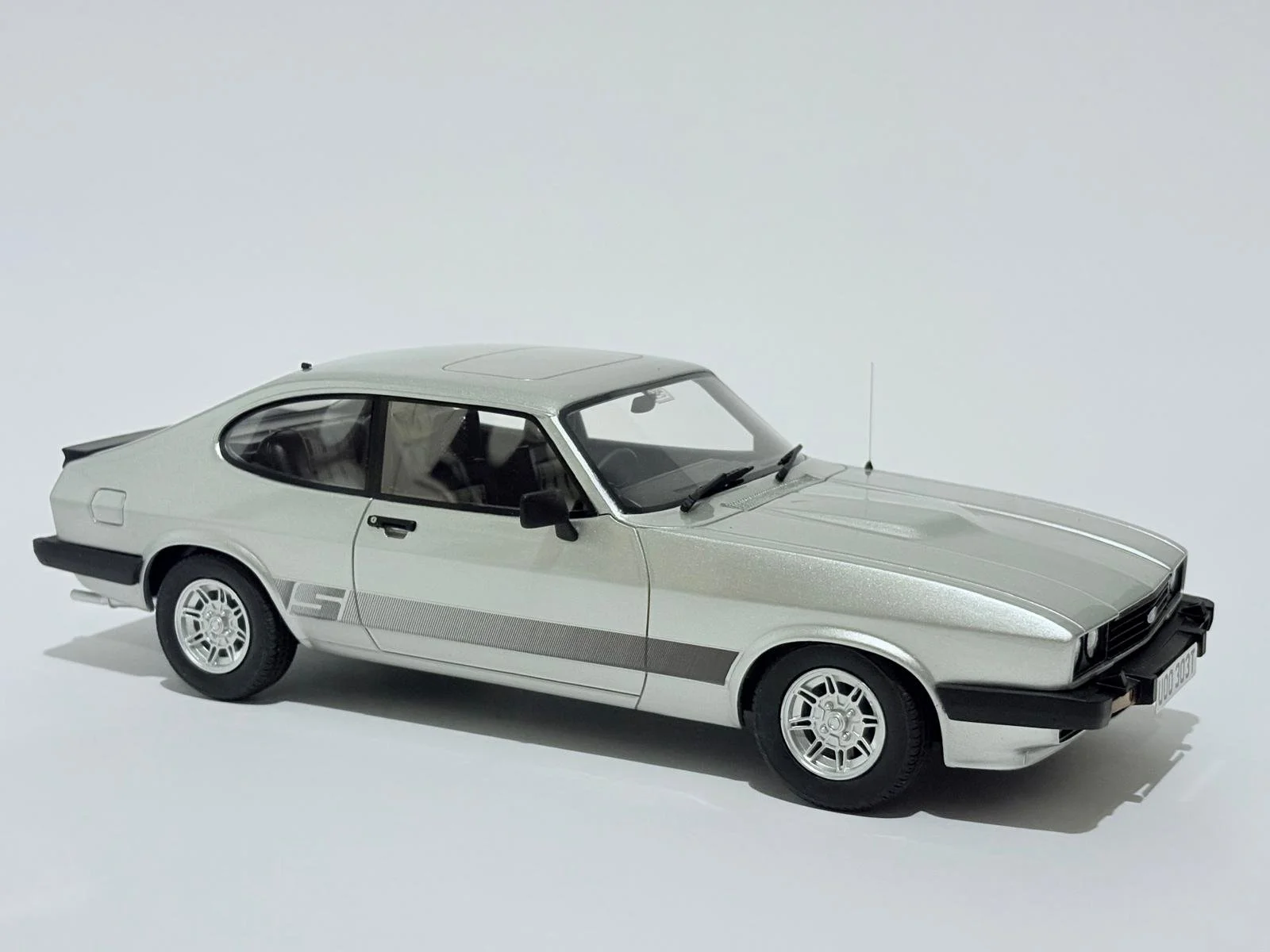 A silver classic model sports car with black accents on a plain white background.