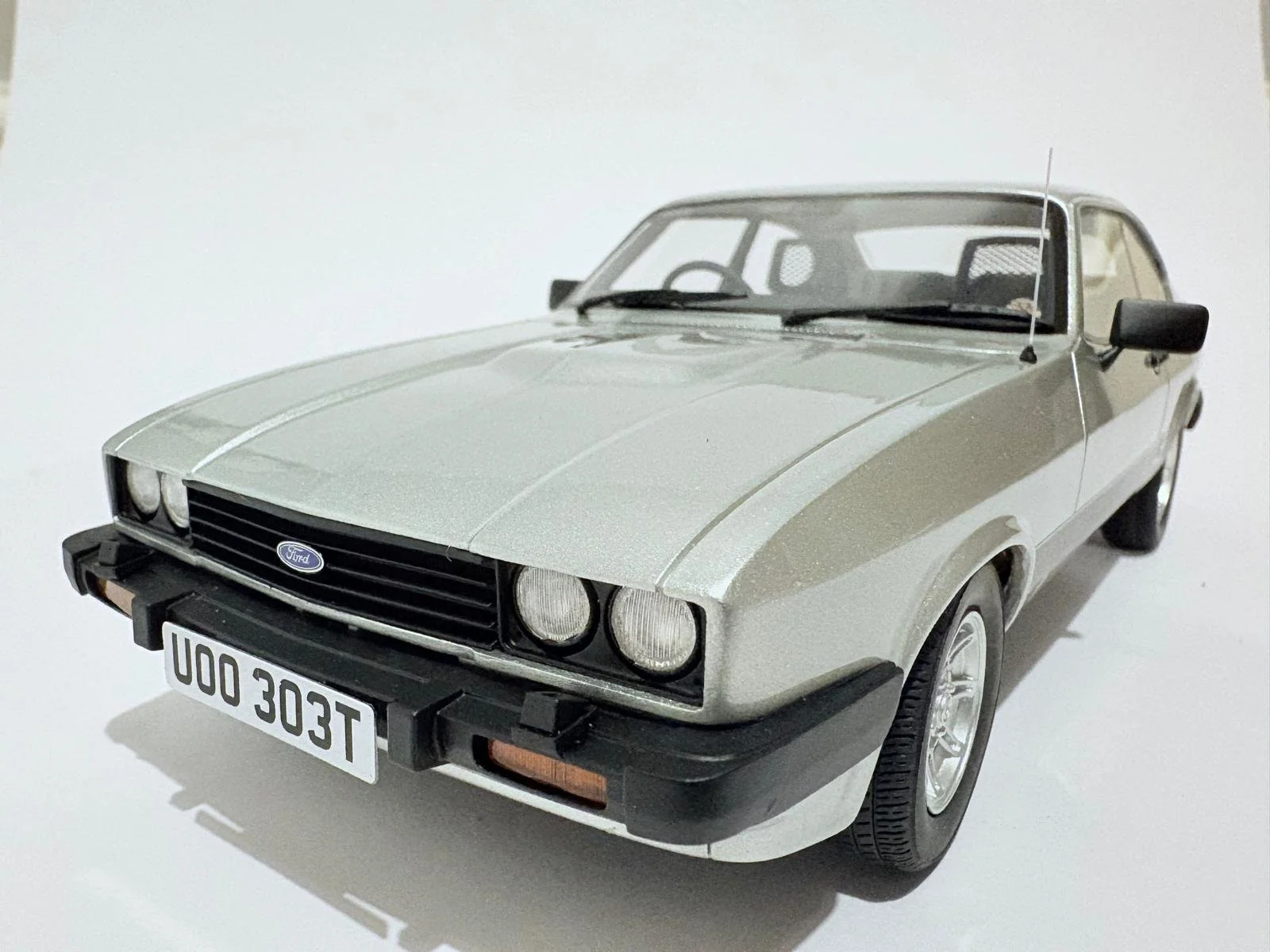 A classic silver Ford car model with black accents and a license plate reading 'UO0 303T' on a plain white background.