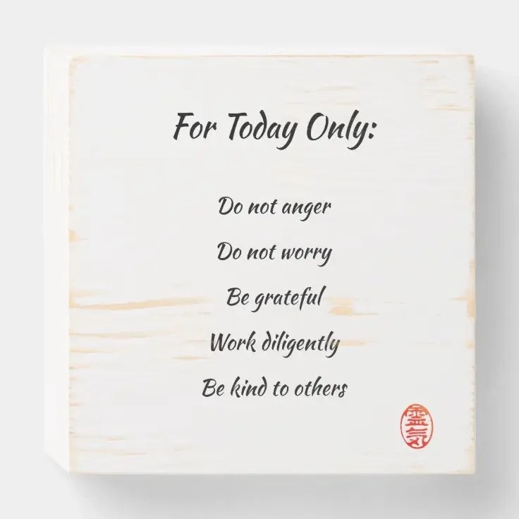 A white wooden plaque with motivational words for the day, including 'Do not anger,' 'Do not worry,' 'Be grateful,' 'Work diligently,' and 'Be kind to others,' written in black script font with a red stamp in the bottom right corner.