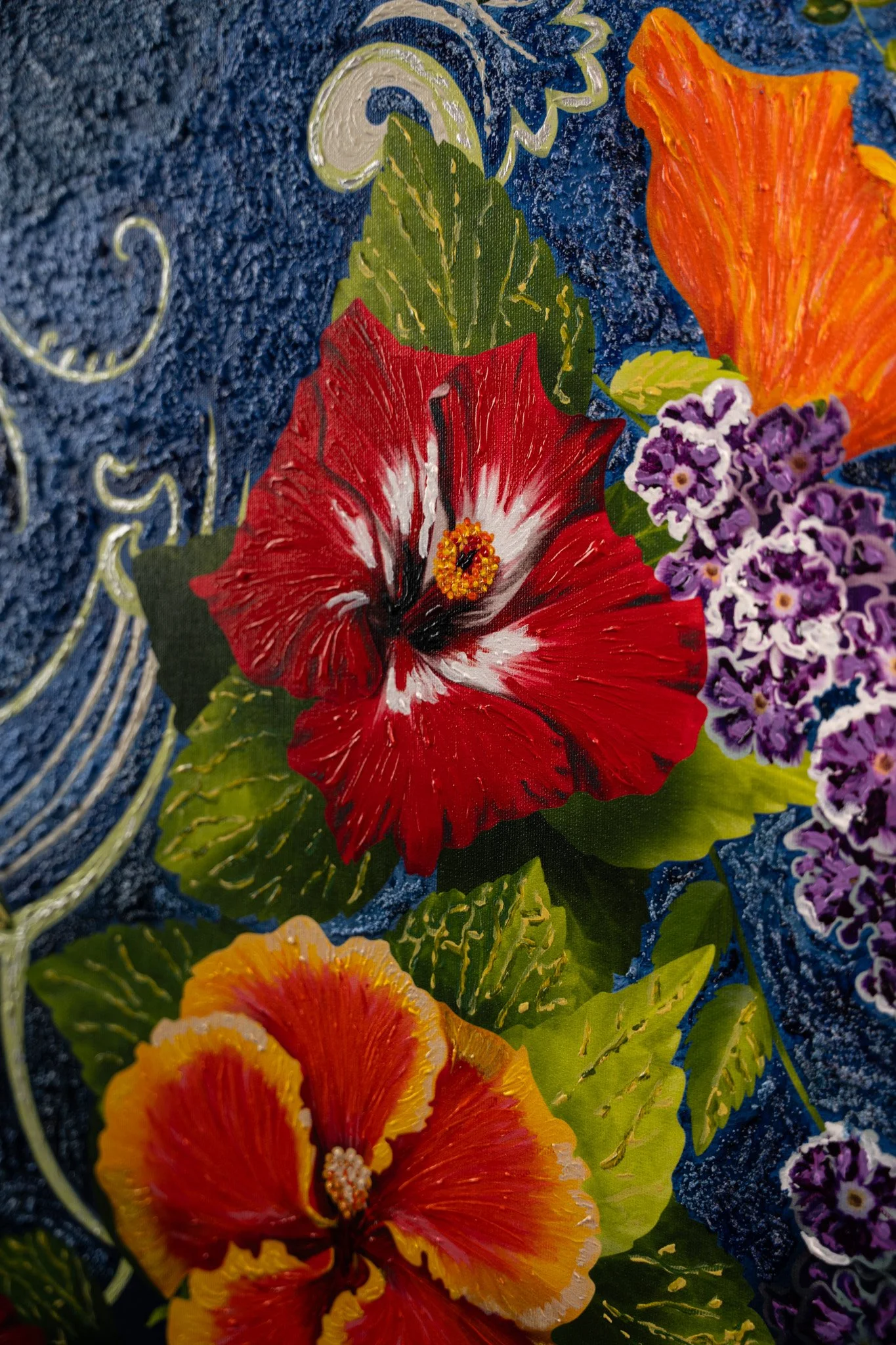 Close-up of a colorful painted floral design on a textured blue surface, featuring red, orange, and purple flowers with green leaves.