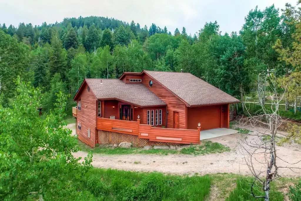 A landscape photo of the red orange house or art studio, surrounded by lots of trees
