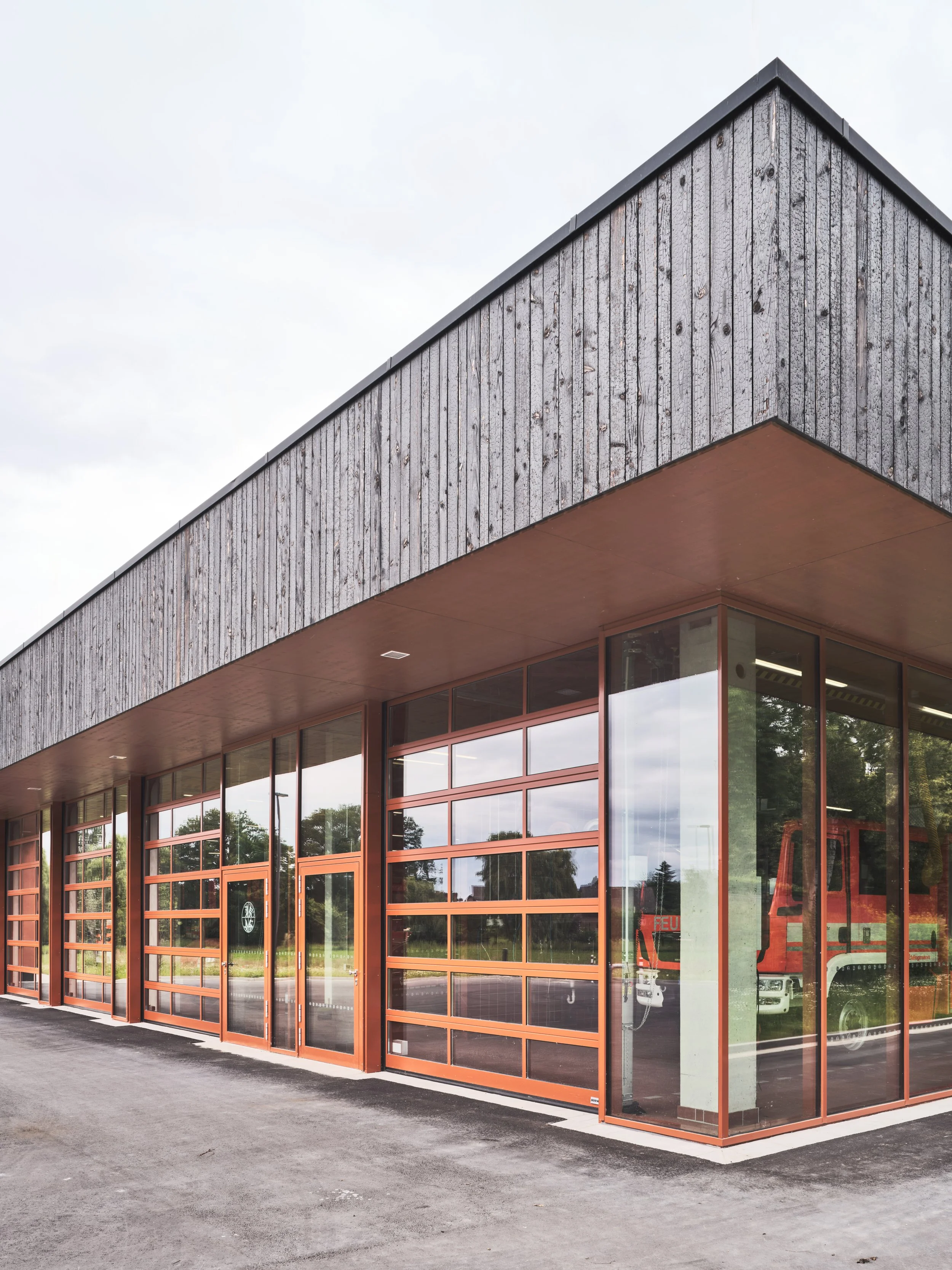 Detailaufnahme der geflammten Schalung aus Douglasienholz an der Fassade des Feuerwehrgerätehauses Westbevern. Die karbonisierte Holzoberfläche variiert im Licht von silbern bis tief schwarz und betont das nachhaltige Design.