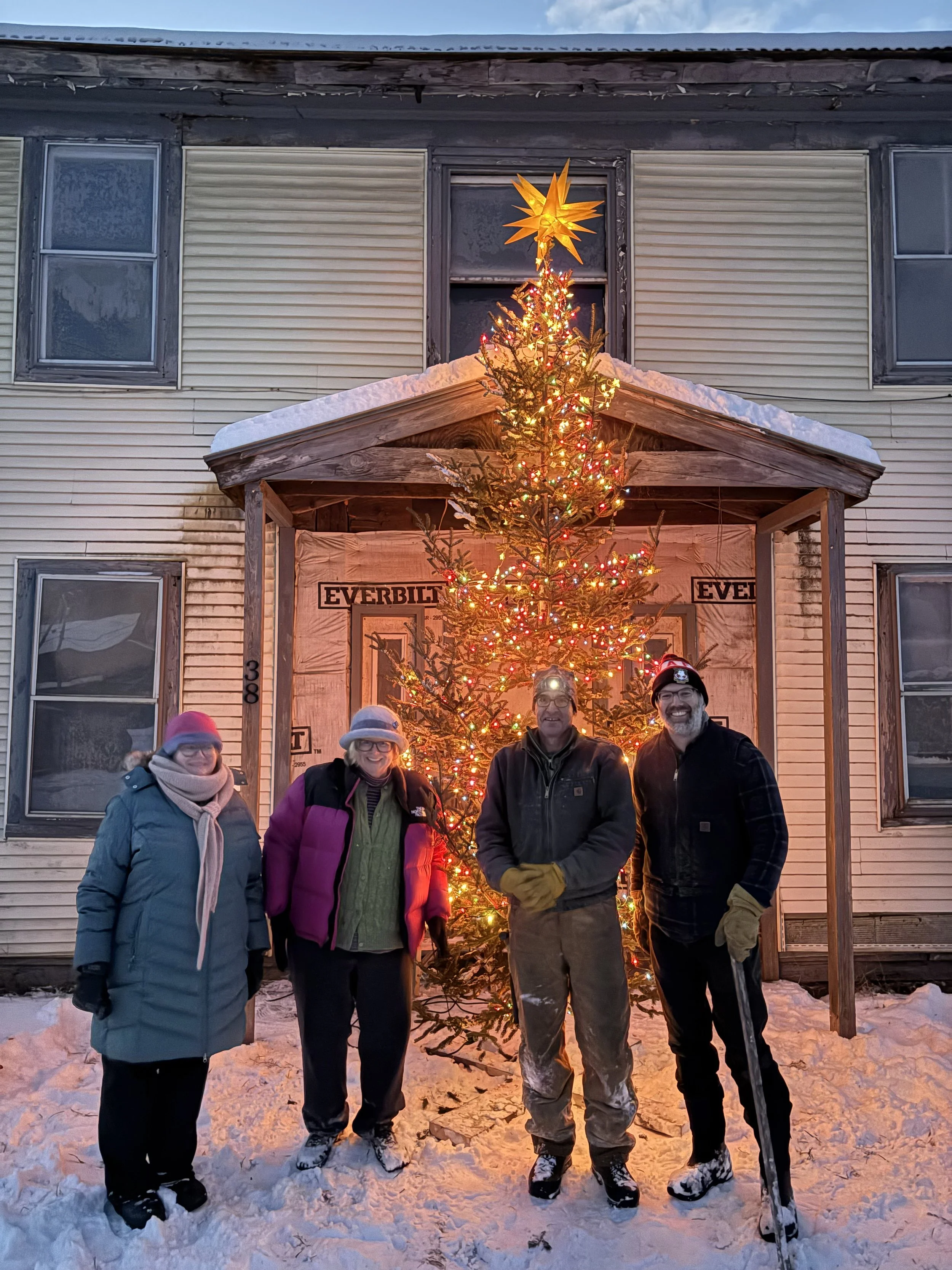 Members of the Snowsville Community Trust stand in front a lighted christmas tree