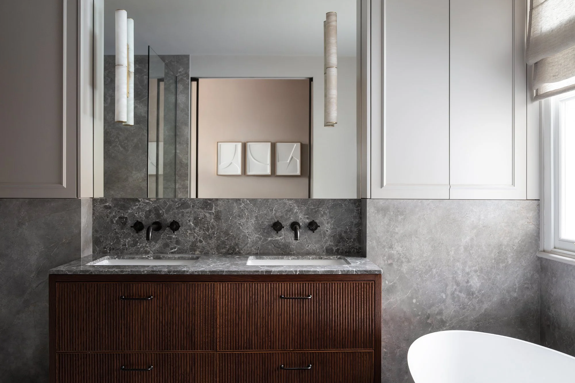 Contemporary bathroom with fluted timber vanity, deep grey marble surfaces, and minimalist lighting, designed by the studio.