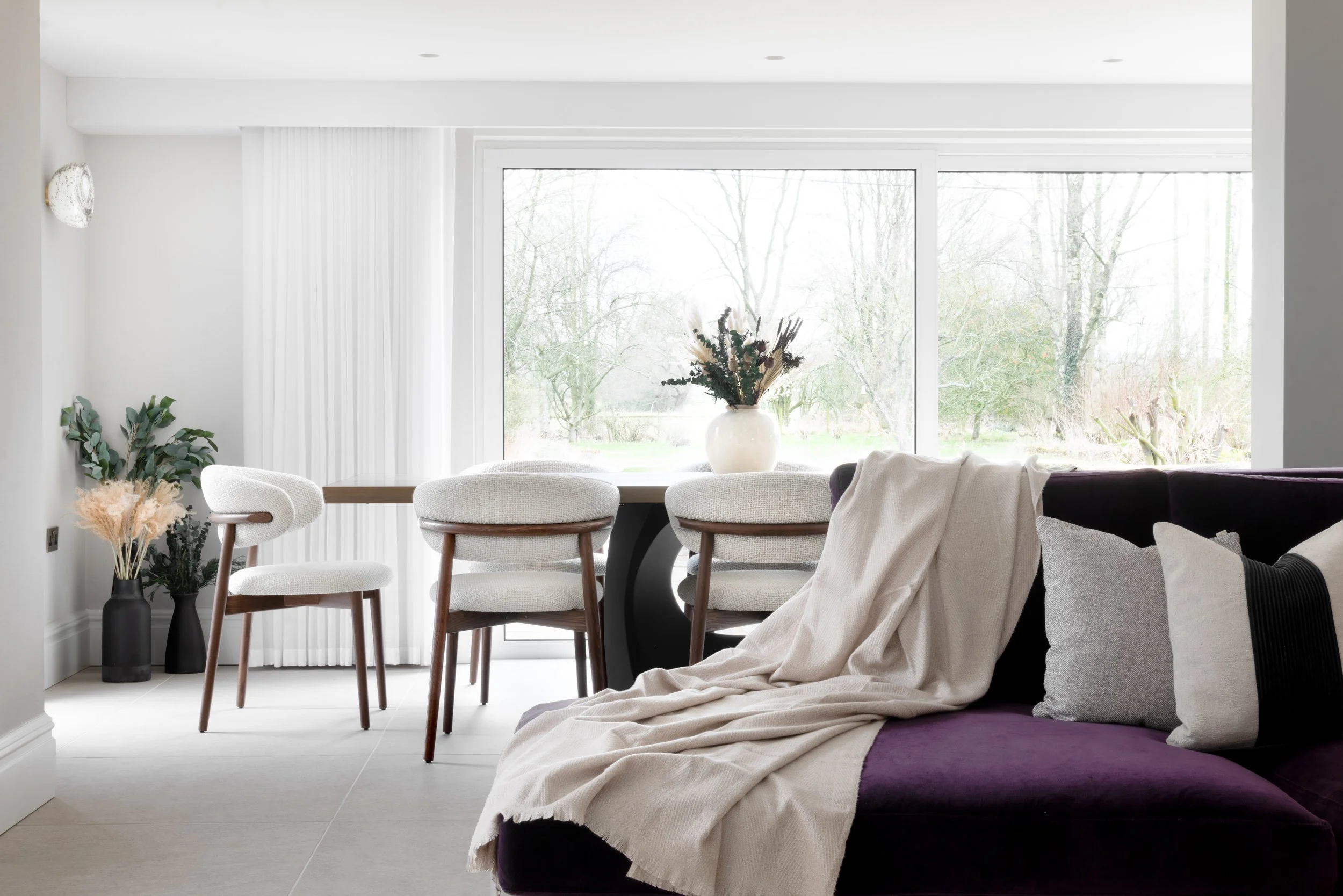 Dining area with upholstered chairs positioned in front of large picture window overlooking garden