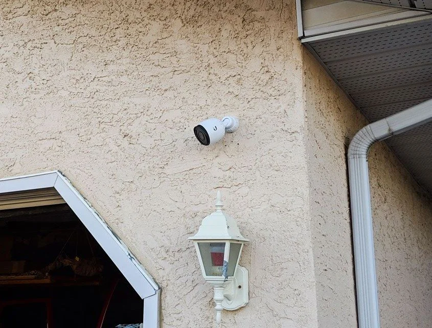Exterior wall with a mounted security camera and a wall-mounted street lamp