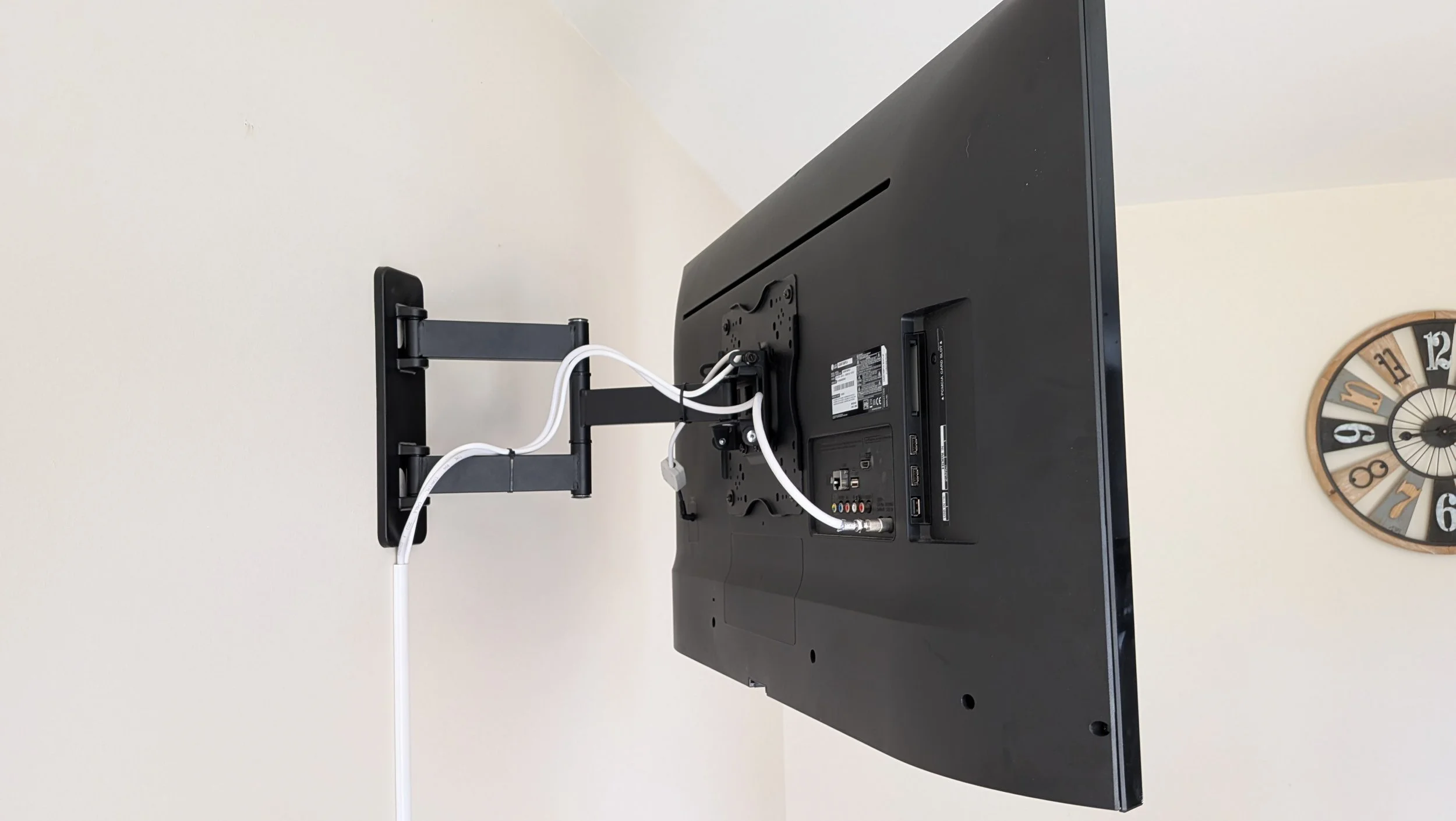 TV & Audio: Back of Flat screen TV mounted on a beige wall above a white radiator, wires trunked from TV to socket - Ballygowen