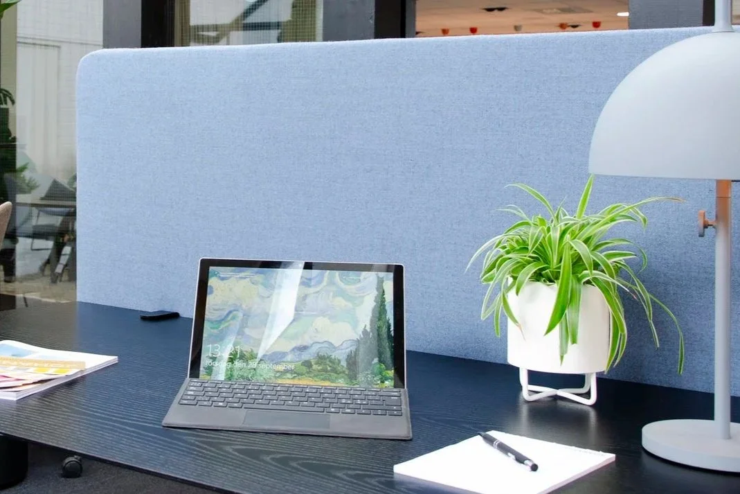 Absorba Tischpaneel Hellblau 66169 hinter Surface-Tablet und Pflanze auf dunklem Bürotisch